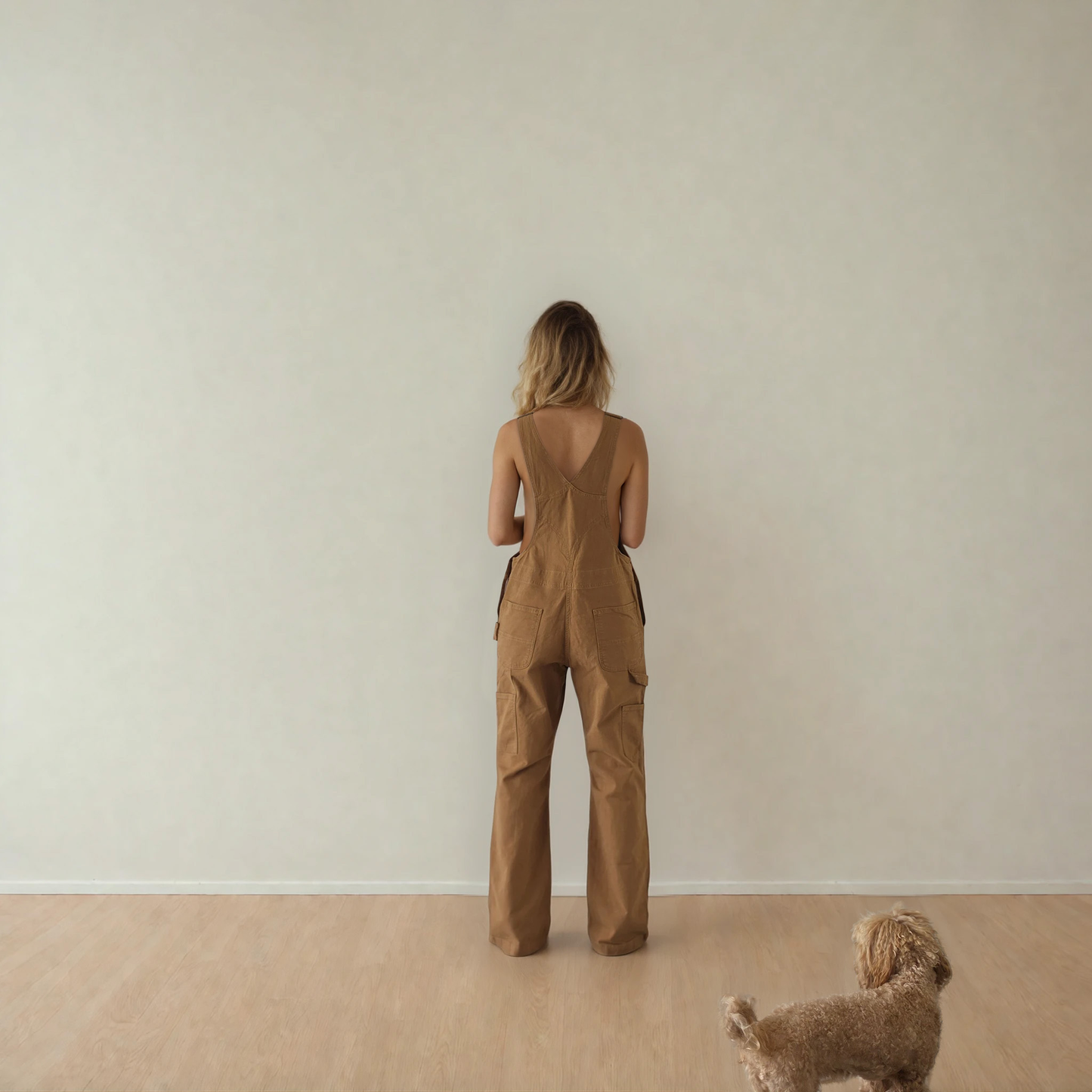Model showing the back view of the Carhartt mustard jumpsuit.