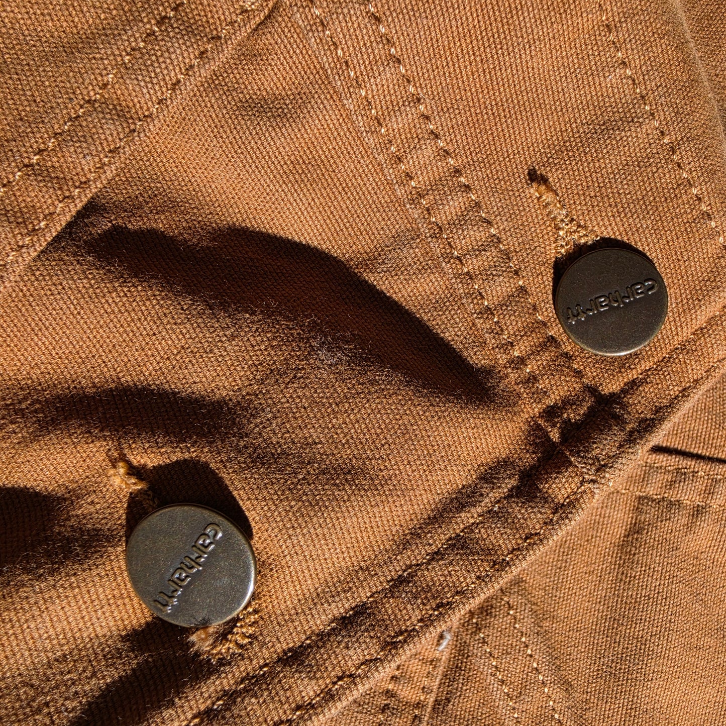 Close up of the button detail on the mustard Carhartt overalls
