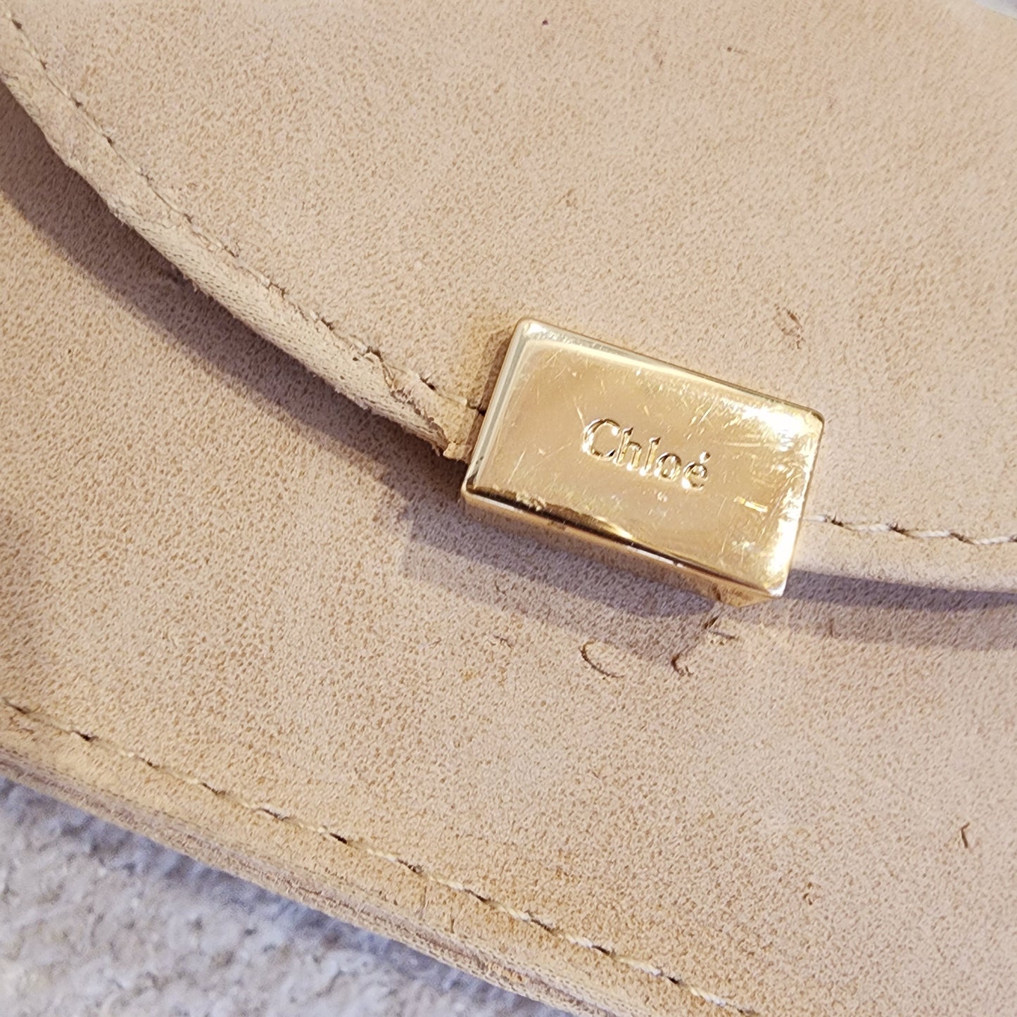 Close up view of the brand plate on the Chloe sunglasses case showing the scratching and wear to case