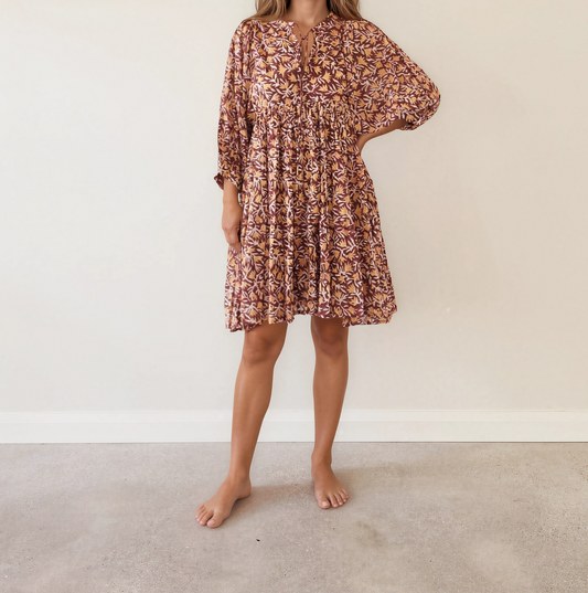 Front view of model wearing the Daughters of India Kyra Mini Dress in the Sumac Print, a maroon, gold and white leaf pattern.