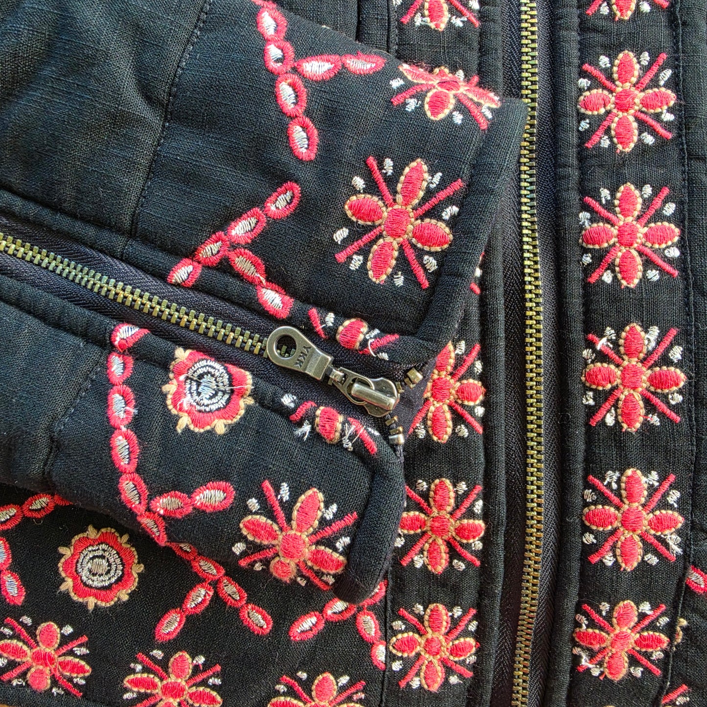Close up view of the Flannel brand Quilted embroidered jacket, showing the sleeve zip detail and floral embroidery.