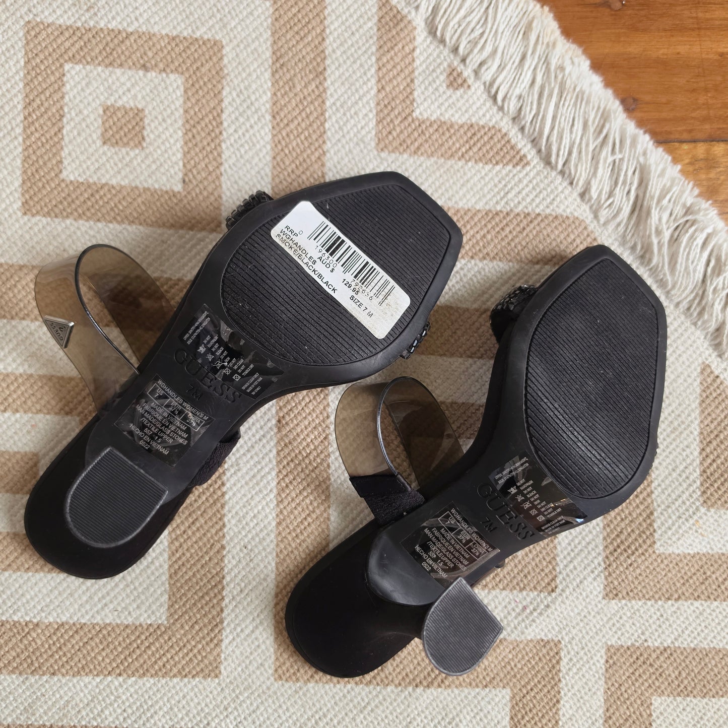 An image of the bottom of the Guess square toe black heels, showing the new heel condition and original price tag