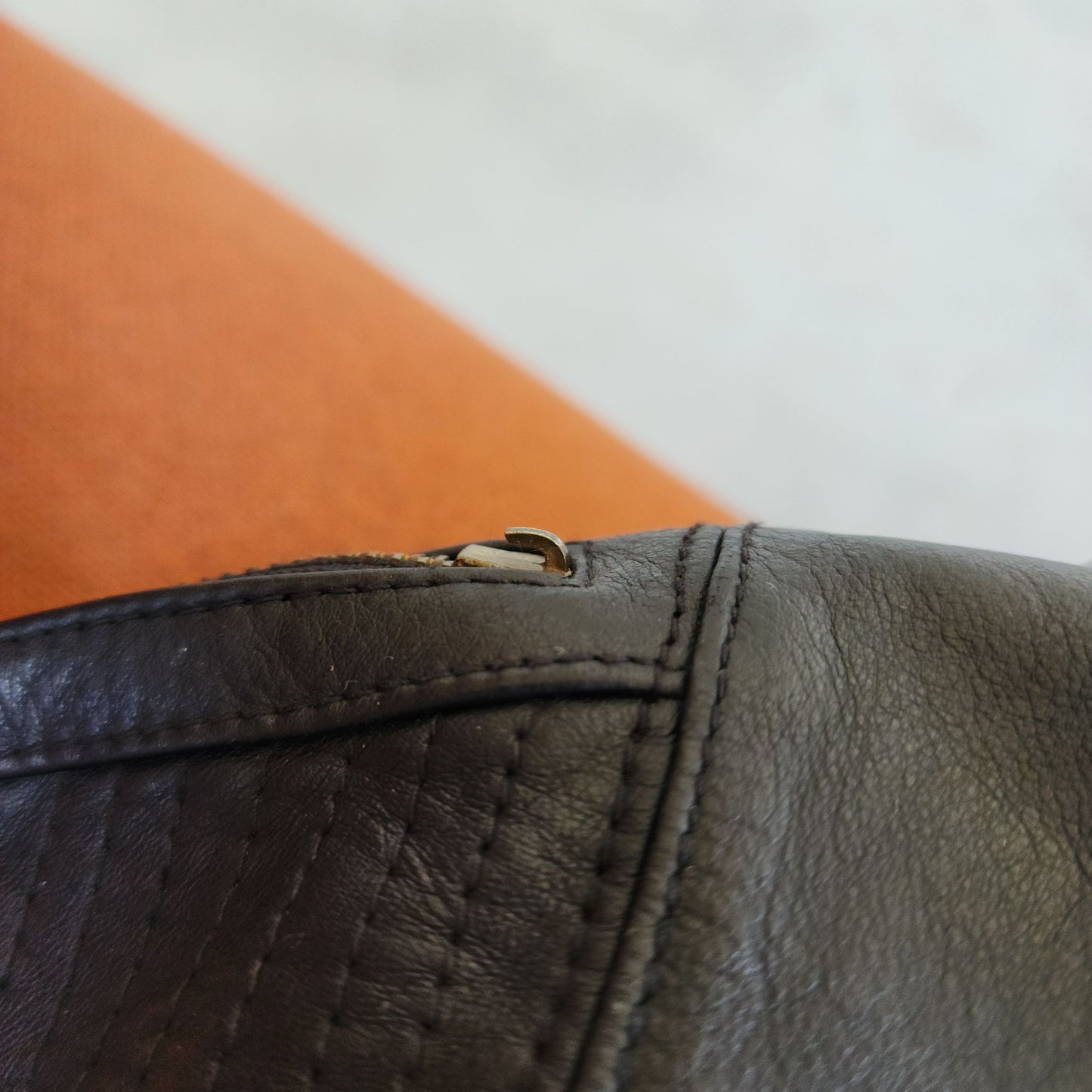 Close up view of the broken zip lever on the high waisted leather shorts.
