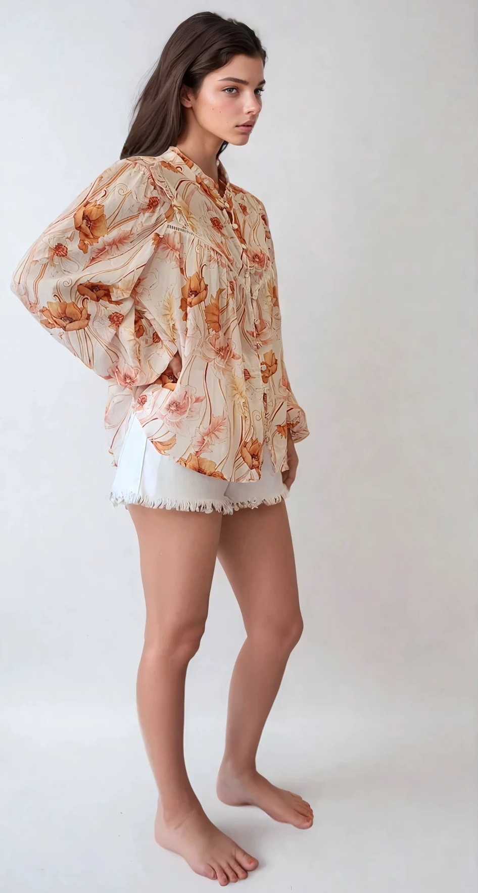 A female model wearing a beige floral Kivari top with long sleeves and lace accents, paired with white shorts.