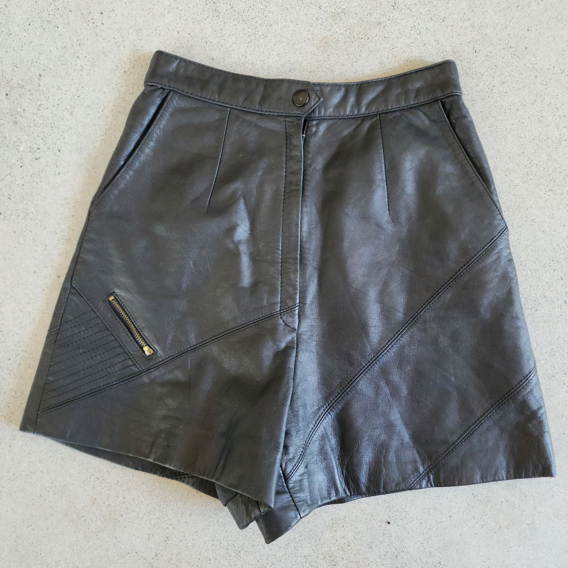 Flat lay of high-waisted short shorts in black paneled leather. 