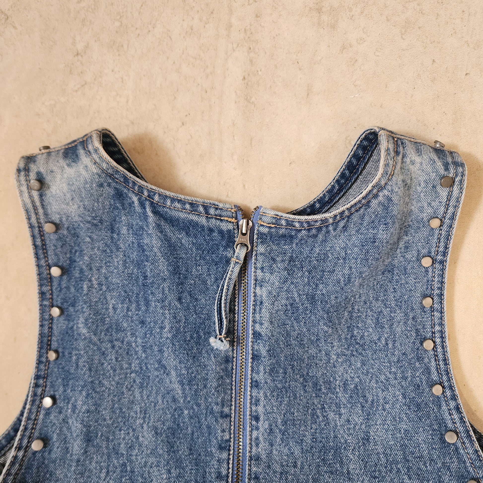 Close-up view of the Lee Denim, denim dress with studded shoulder details and zip up back. 