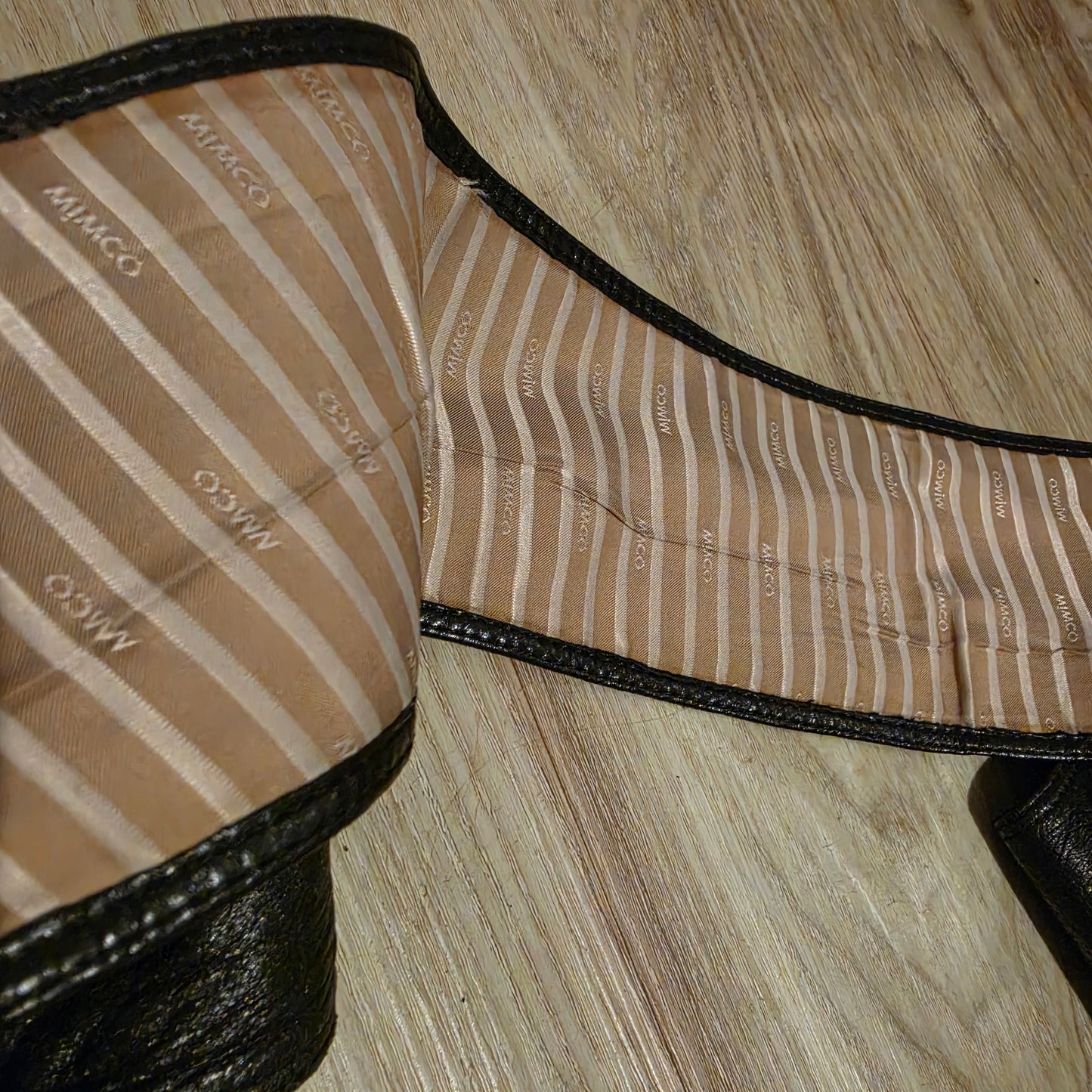 Close up image of the black wide Mimco leather belts lining showing creasing and discolouration of the fabric.