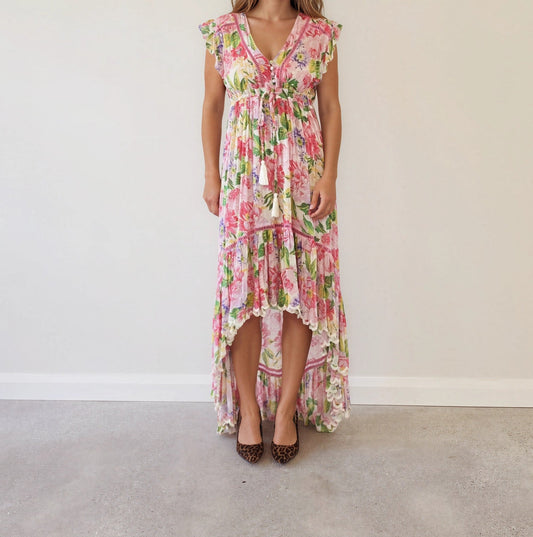 Front view of Miss June Paris Holly floral high-low maxi dress with ruffle sleeves, tassel tie waistline and scalloped cascading hem, worn with leopard print heels