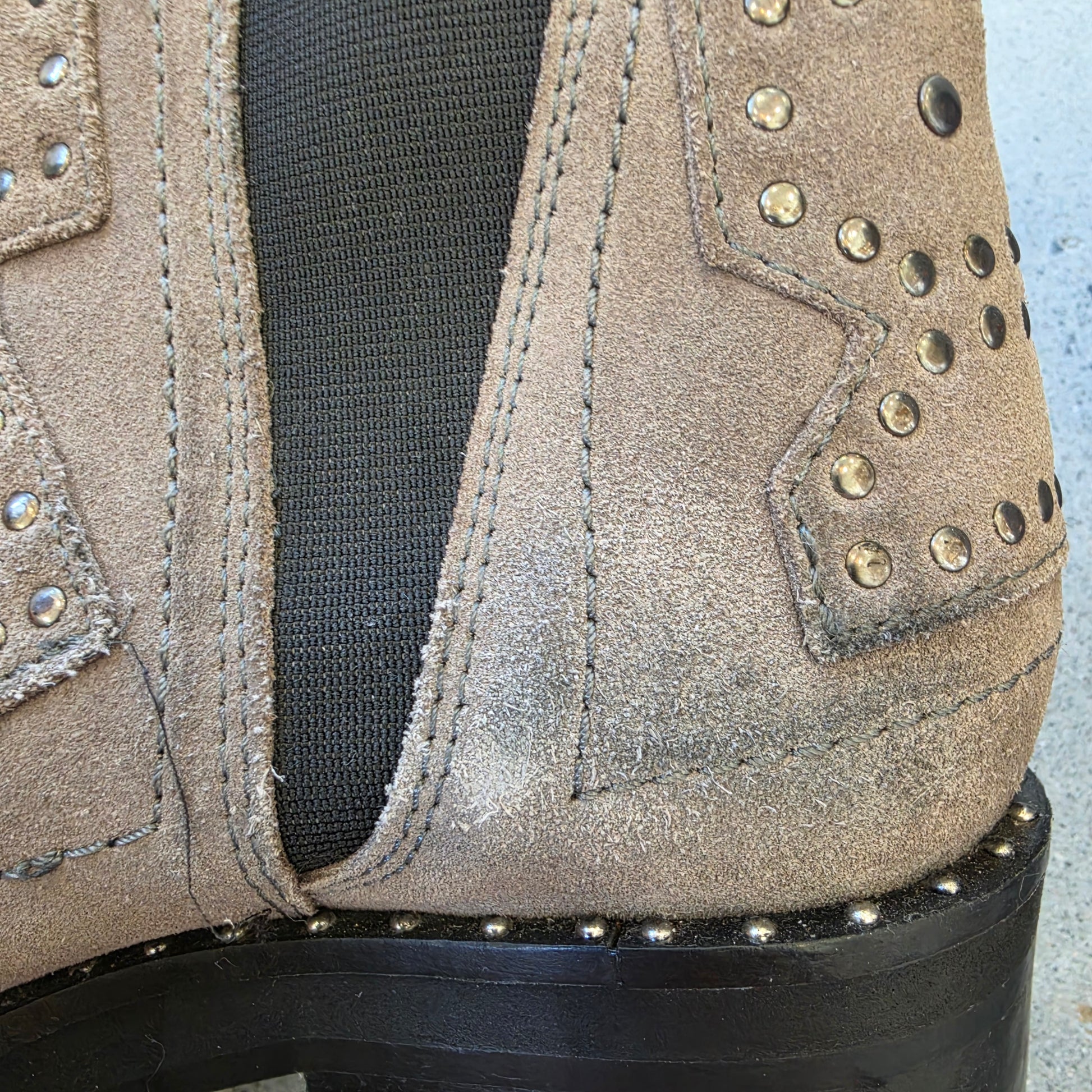View of the back of one of the One Teaspoon suede boots with stacked heels, showing the discolouration and stud trim