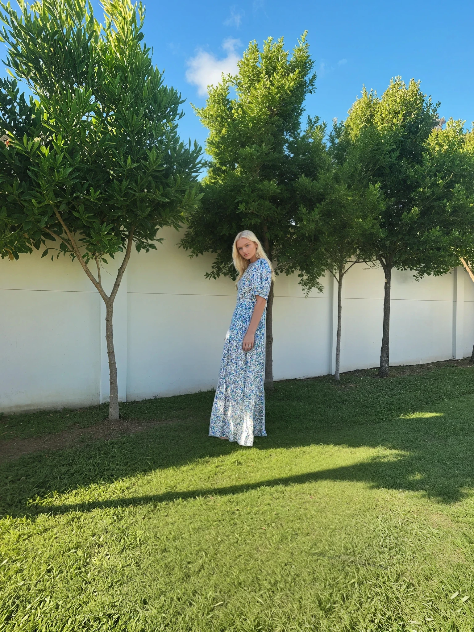 Model showing the side view of the Oak Meadow blue floral maxi dress in size small.