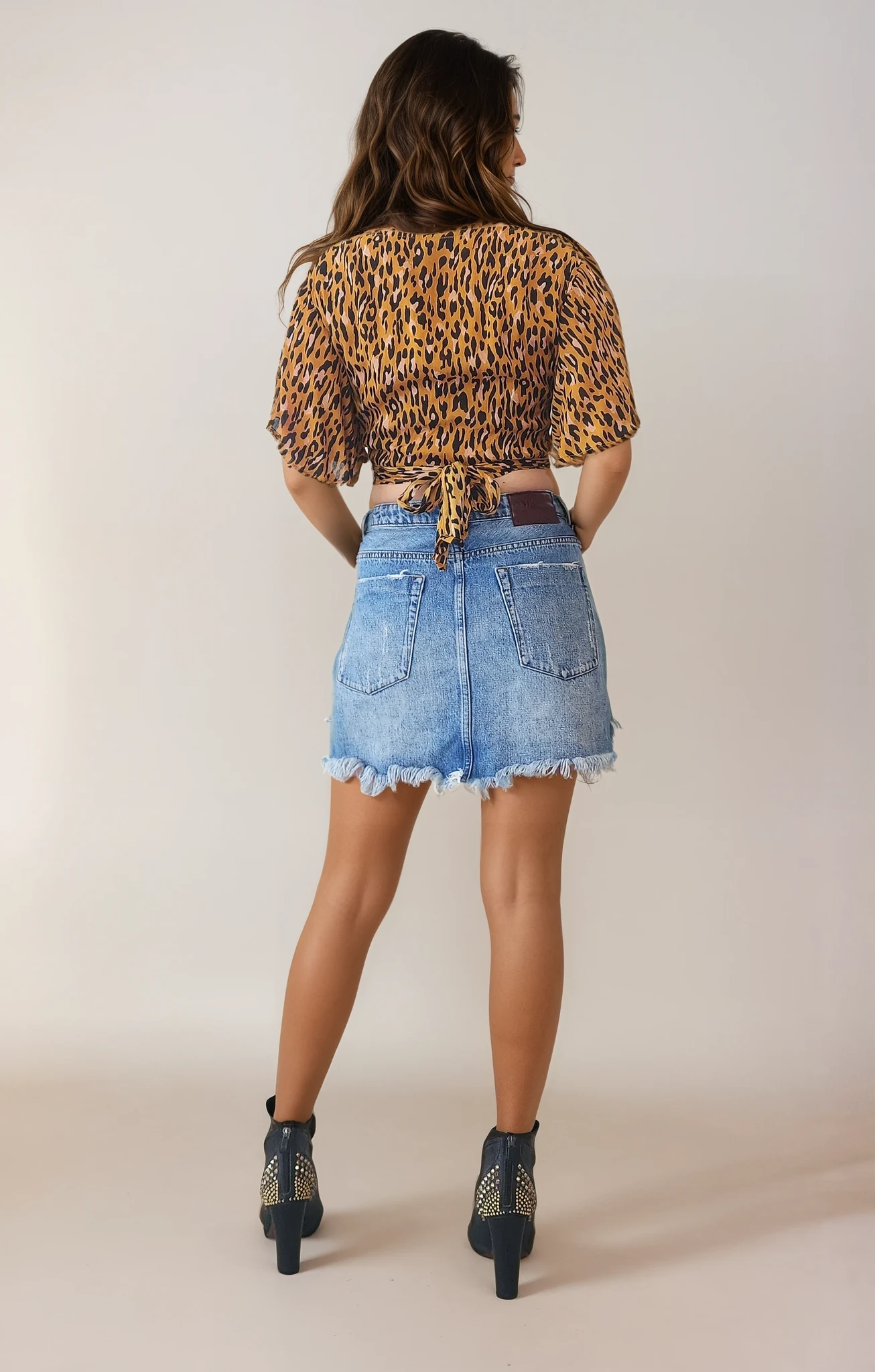 Image of model wearing the One Teaspoon 2020 Mini Skirt, showing the back view, with factory distressing and raw hem