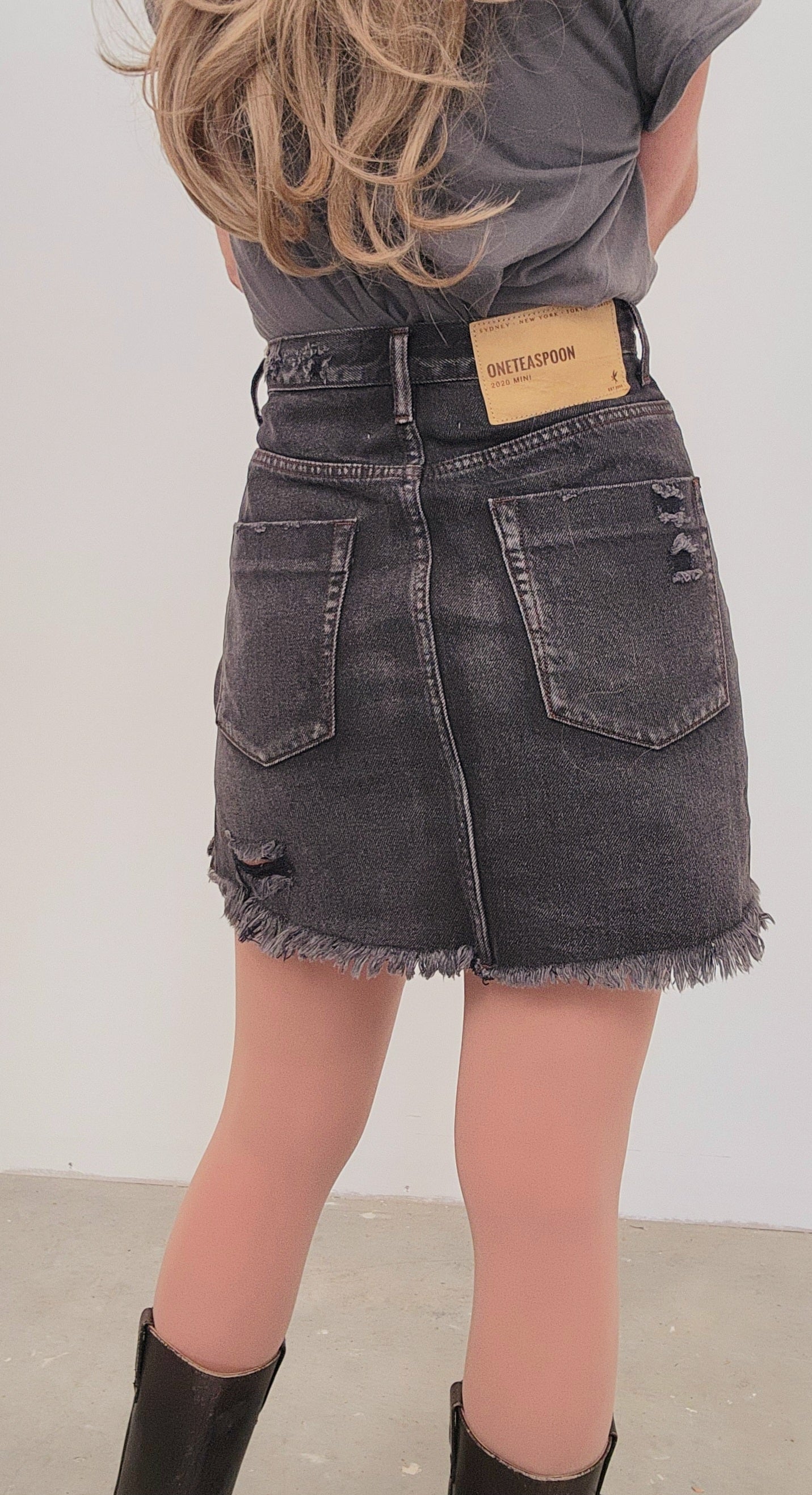 Image showing back of the One Teaspoon 2020 Mini skirt in charcoal showing the factory distress and raw hemline