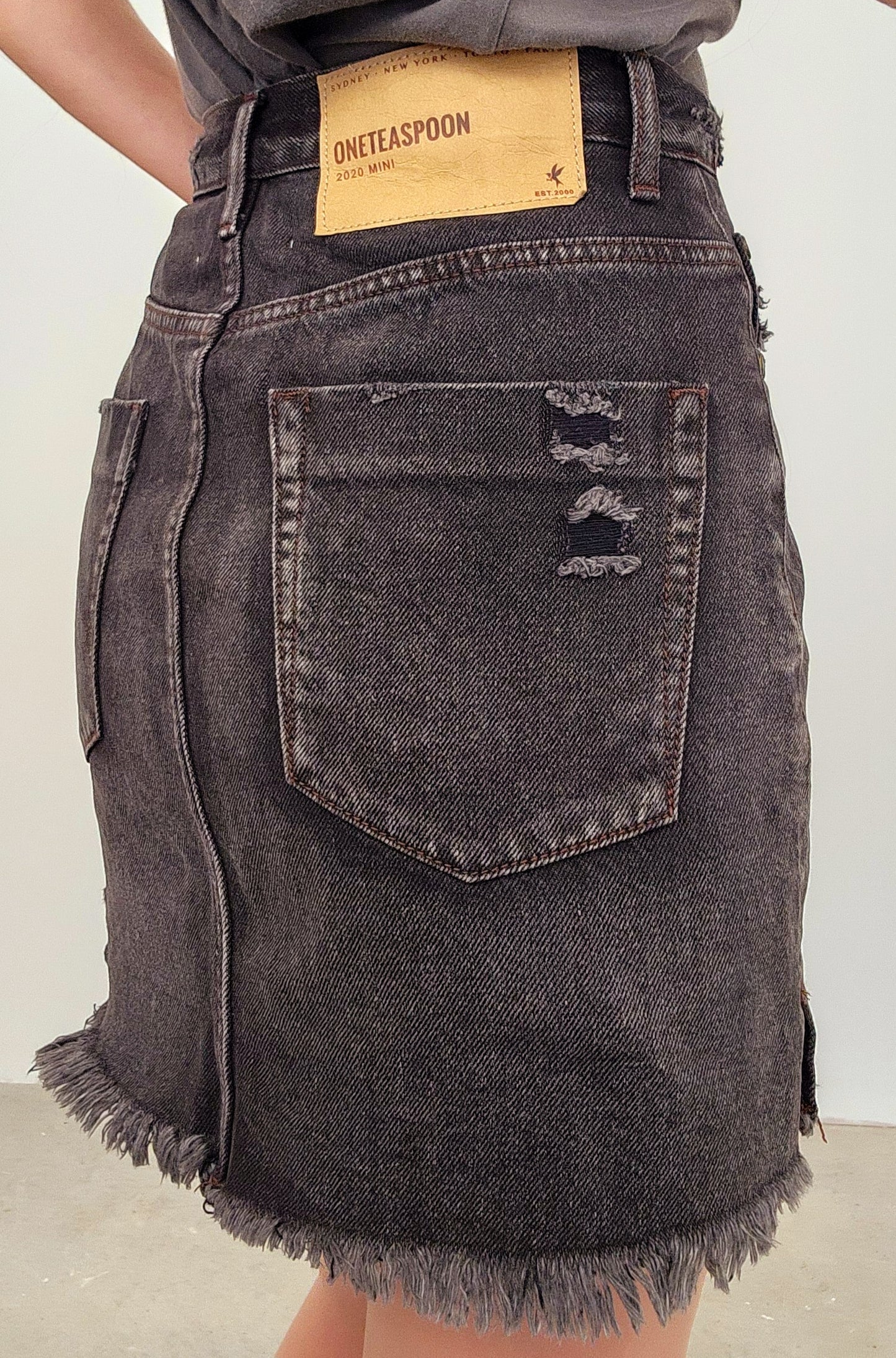 Image showing the One Teaspoon 2020 Mini skirt label, distressed details and raw hemline in charcoal.