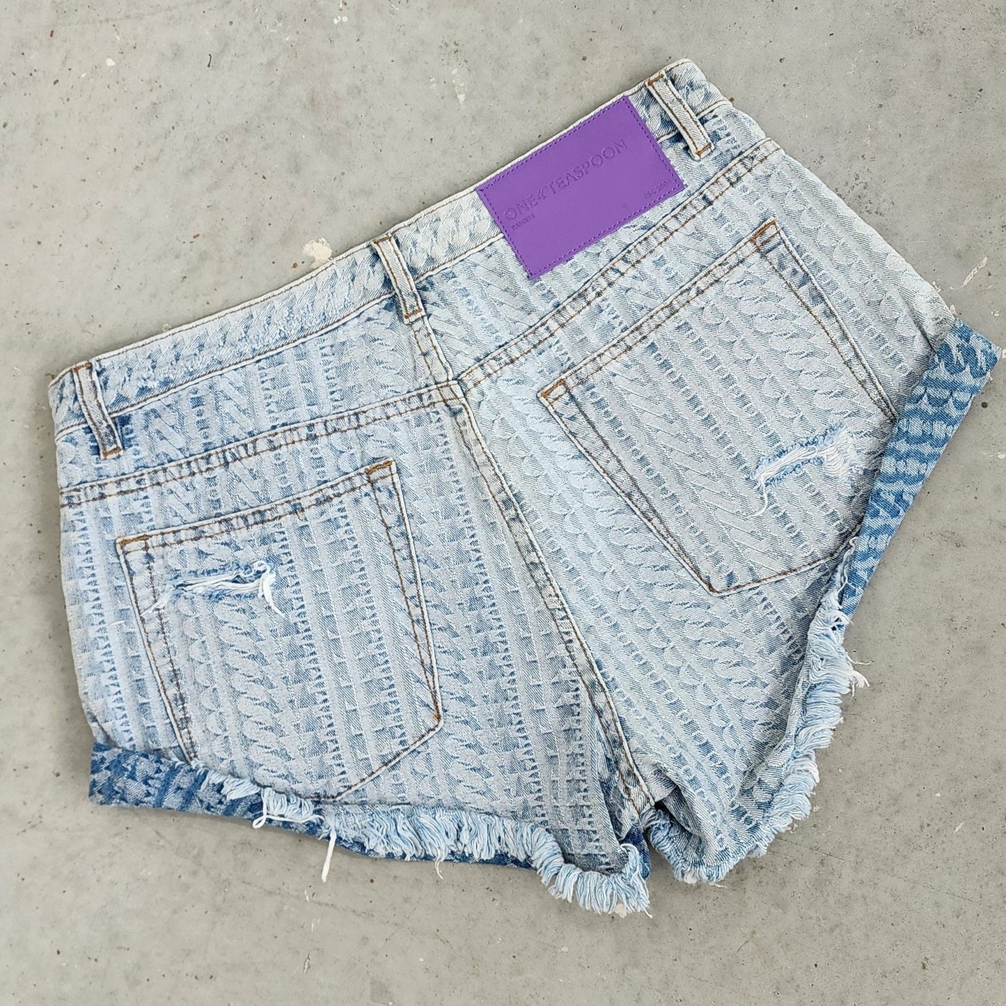 Image of the One Teaspoon bandit shorts, showing the exclusive print "on repeat", the One Teaspoon back label tag and factory distress