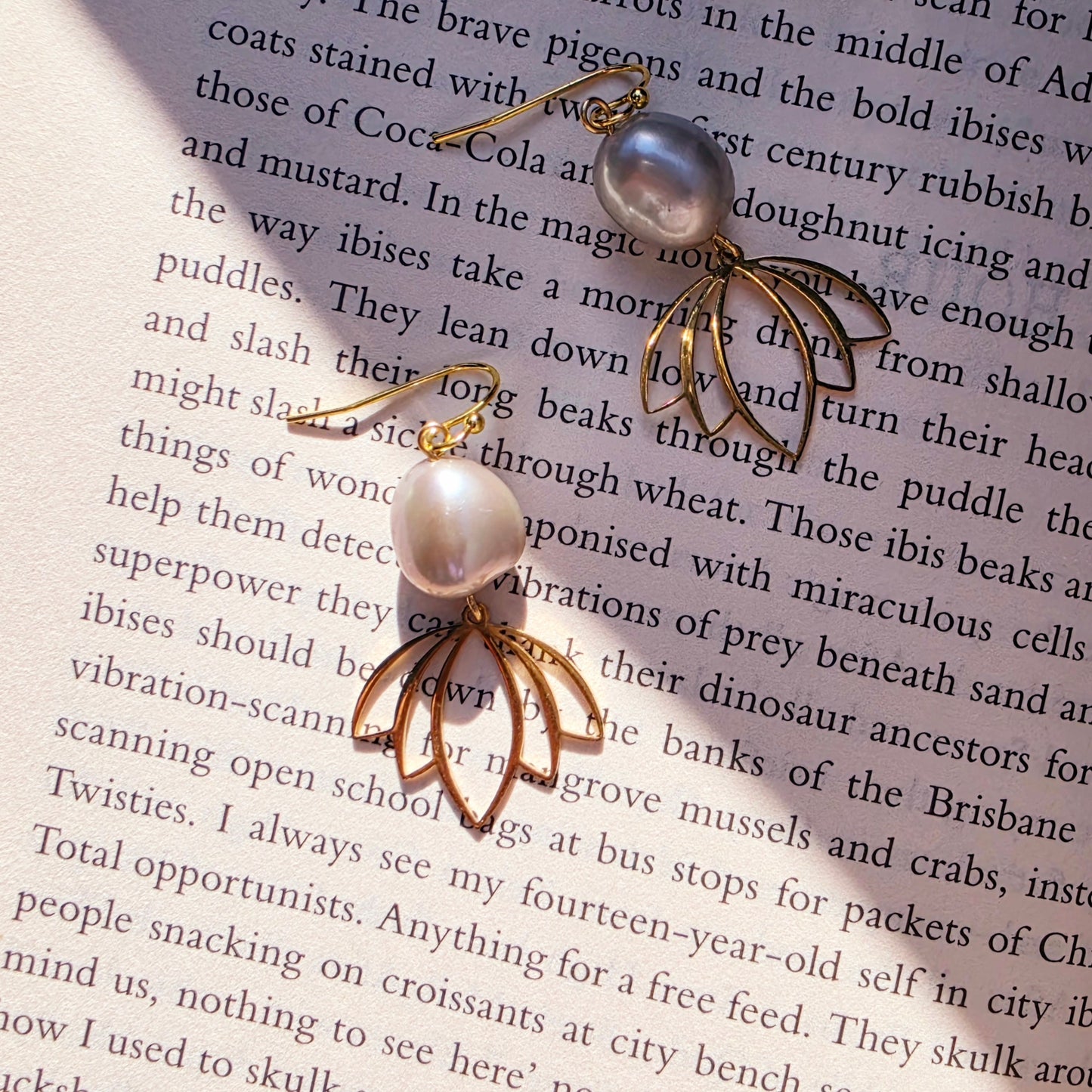 Image showing the Qoqa pearl and gold-toned statement earrings on book background.
