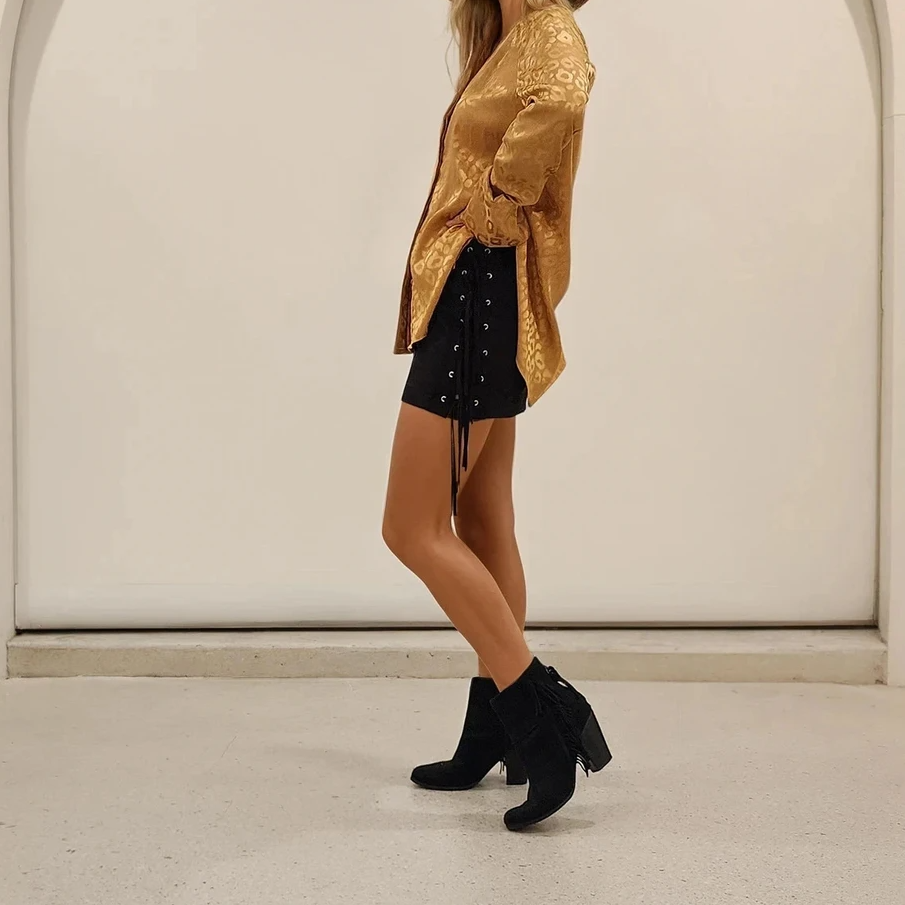 Side view of the Rise of Dawn fringe mini skirt, showing the eyelets and frineg worn with the Acoa leopard blouse.