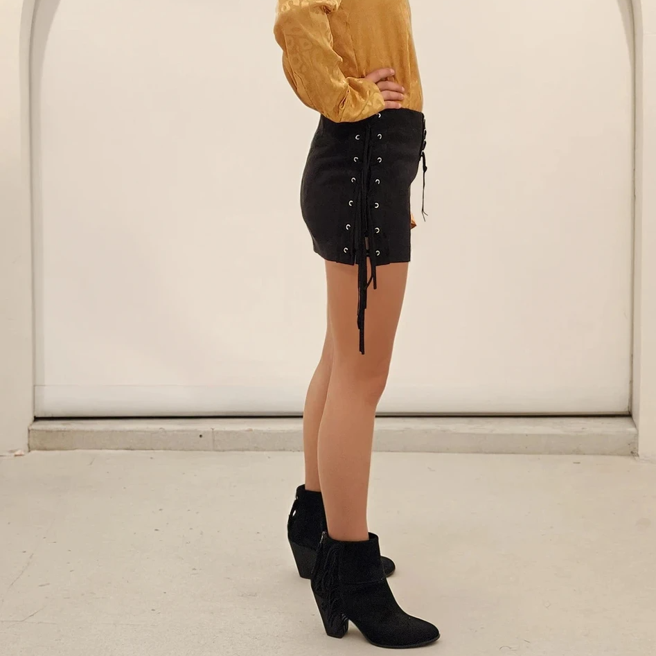 Side View of the Rise of Dawn Fringe Skirt showing the eyelets, fringe and mini style.