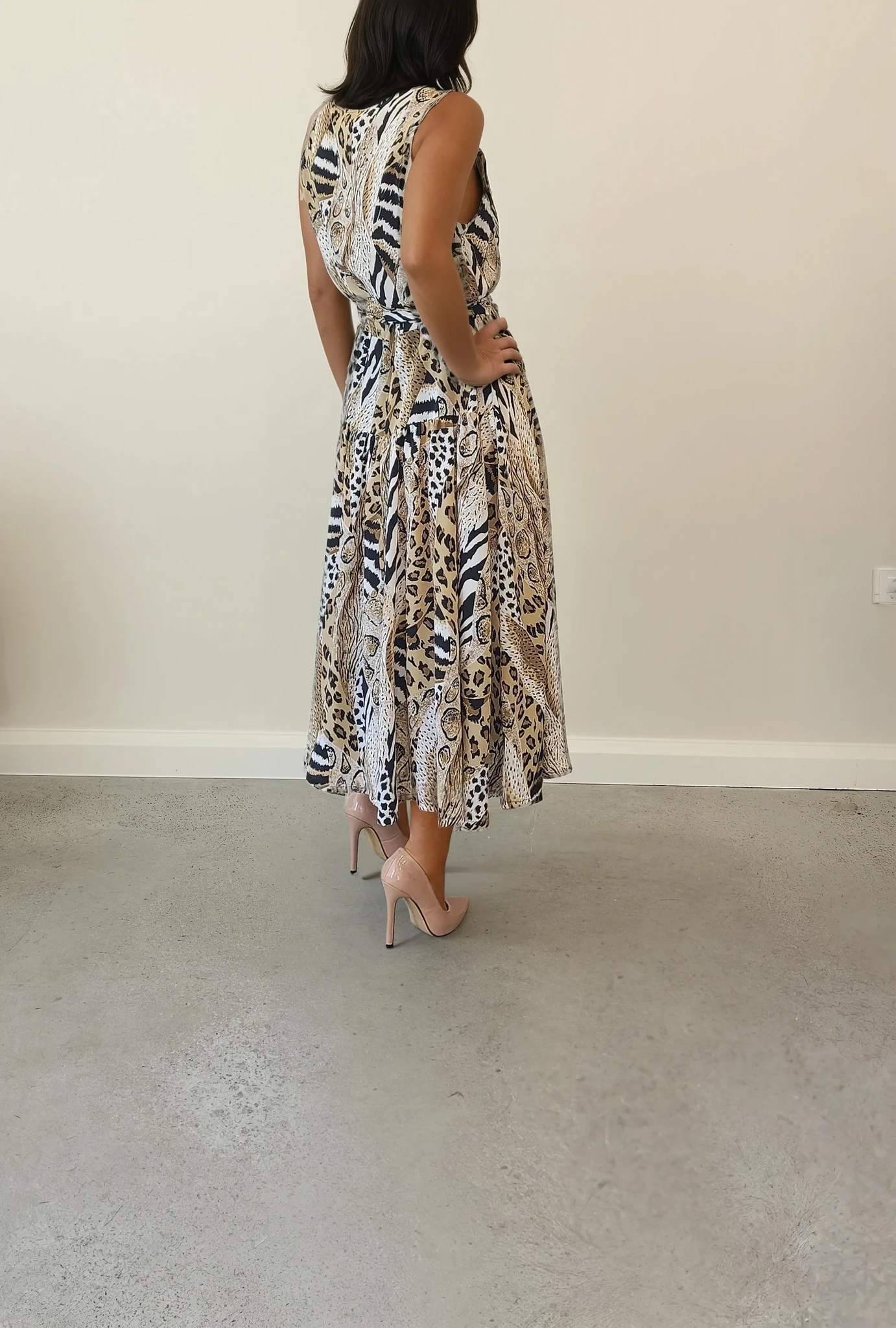 The back view of a model wearing the Sally Browne vintage dress in animal print, showing the drape of the dress and the midi style.