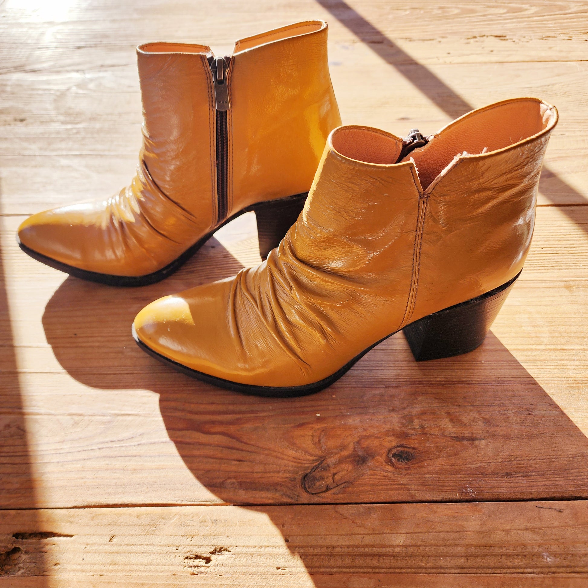 Left-side angle of the Sempre Di mustard leather ankle boots, highlighting the curved heel and creased front detail.
