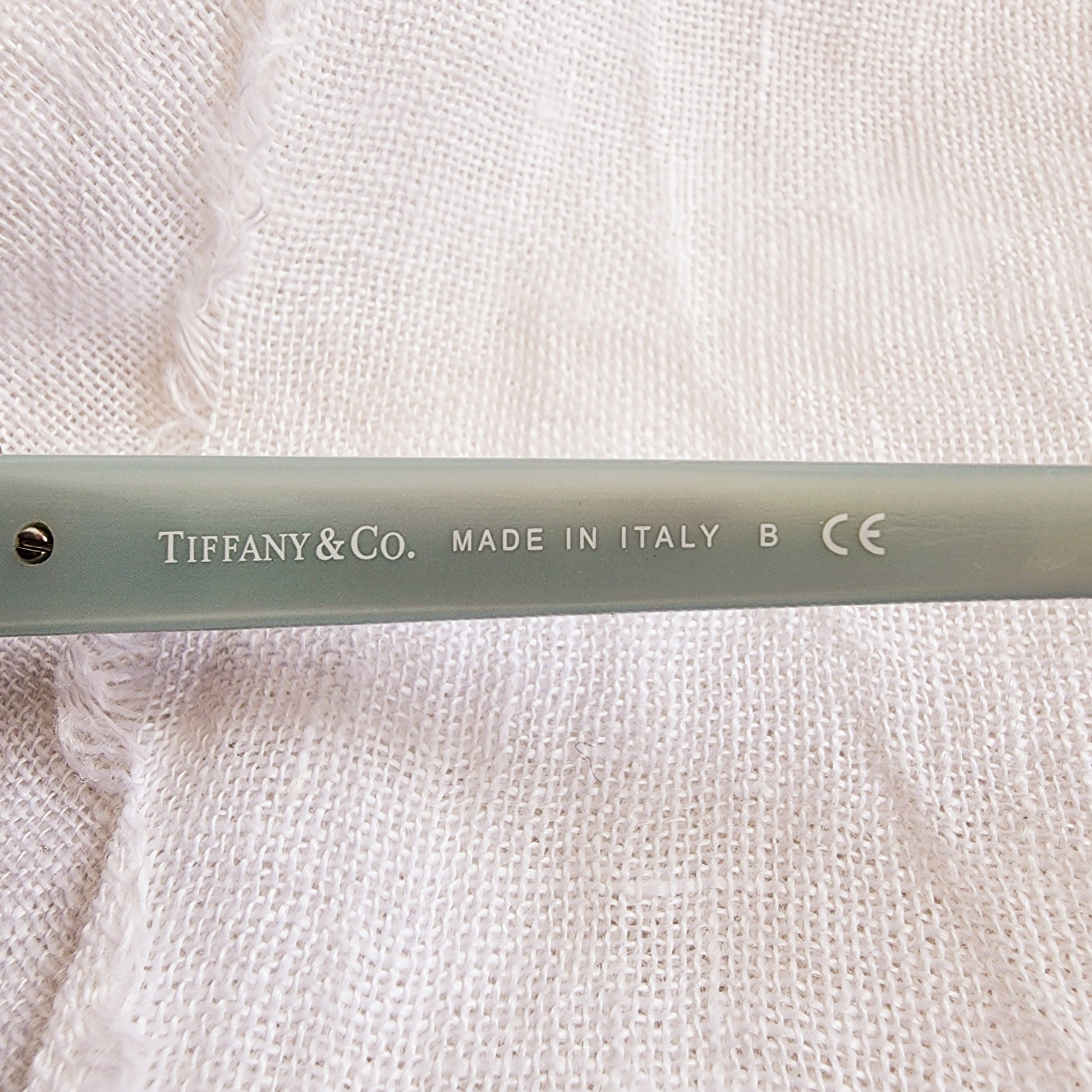 Close up of the left temple on the Tiffany & Co sunglasses, showing brand name and made in Italy stamp.