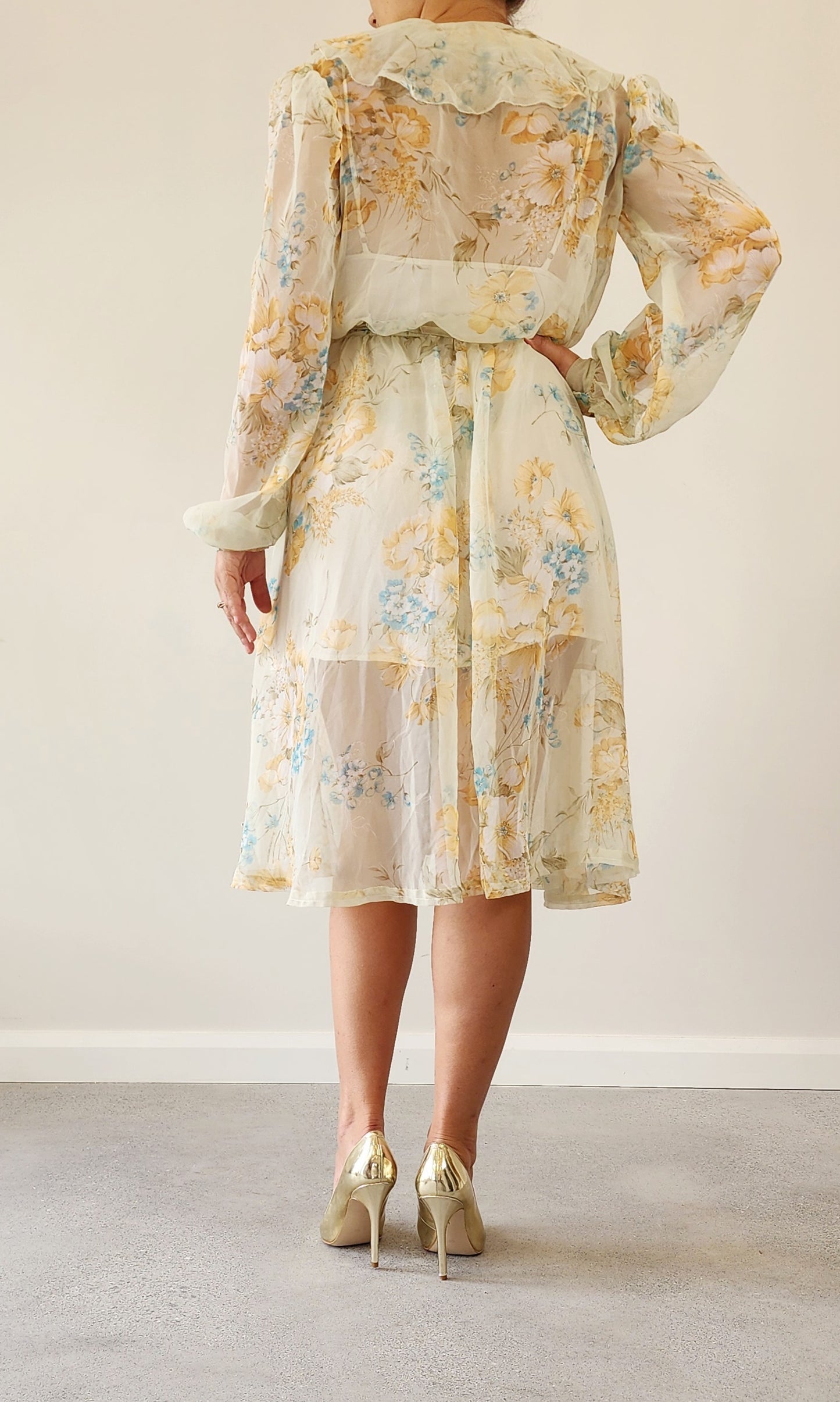 Back view of model wearing the vintage floral 70s dress, showing the soft sleeves and midi fall of the hemline.