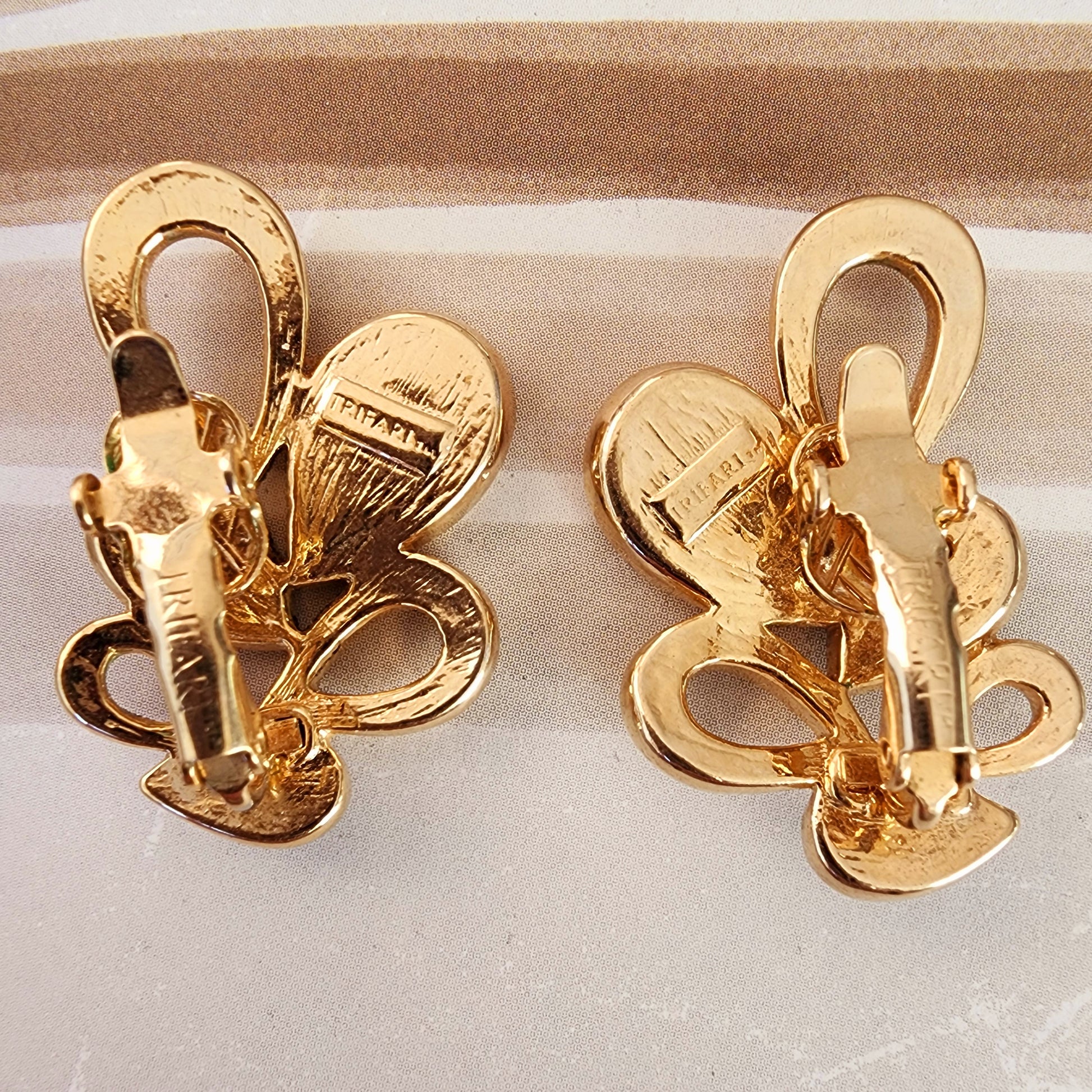 Back view of the vintage Trifari clip-on earrings, showing the gold tone and designer brand stamps.