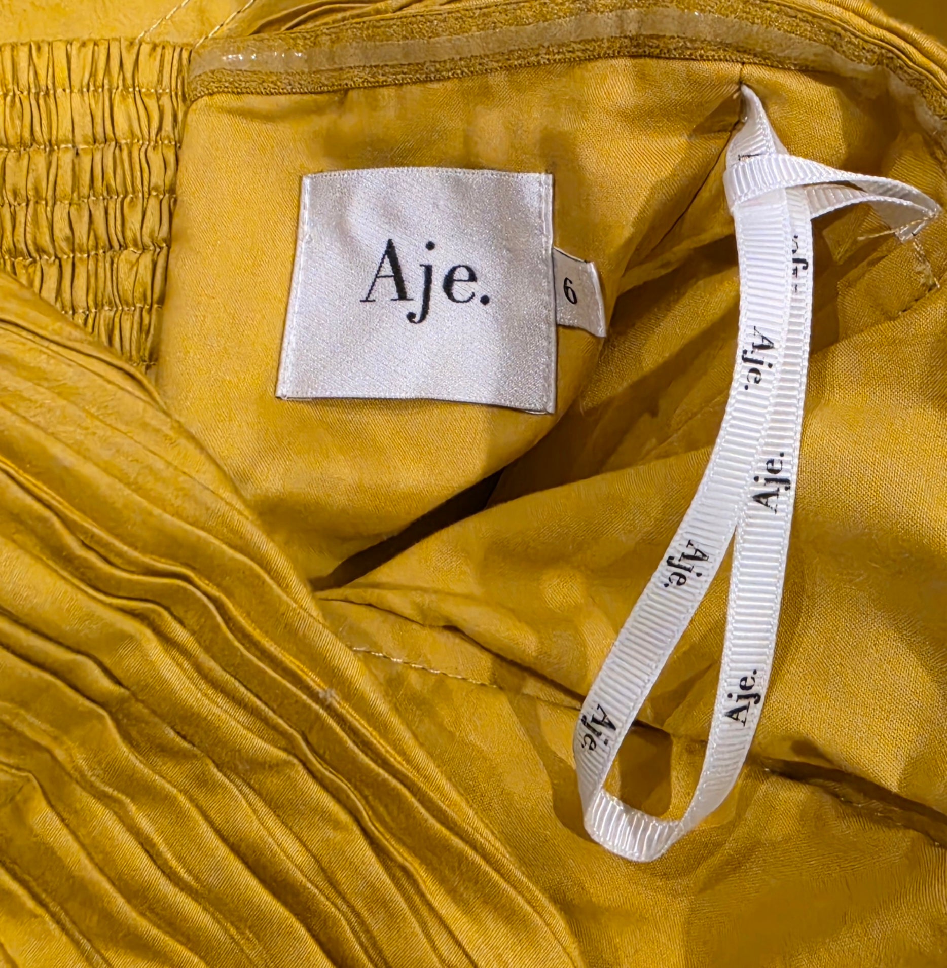 Aje label and internal hanger ribbon inside mustard yellow Marigold dress