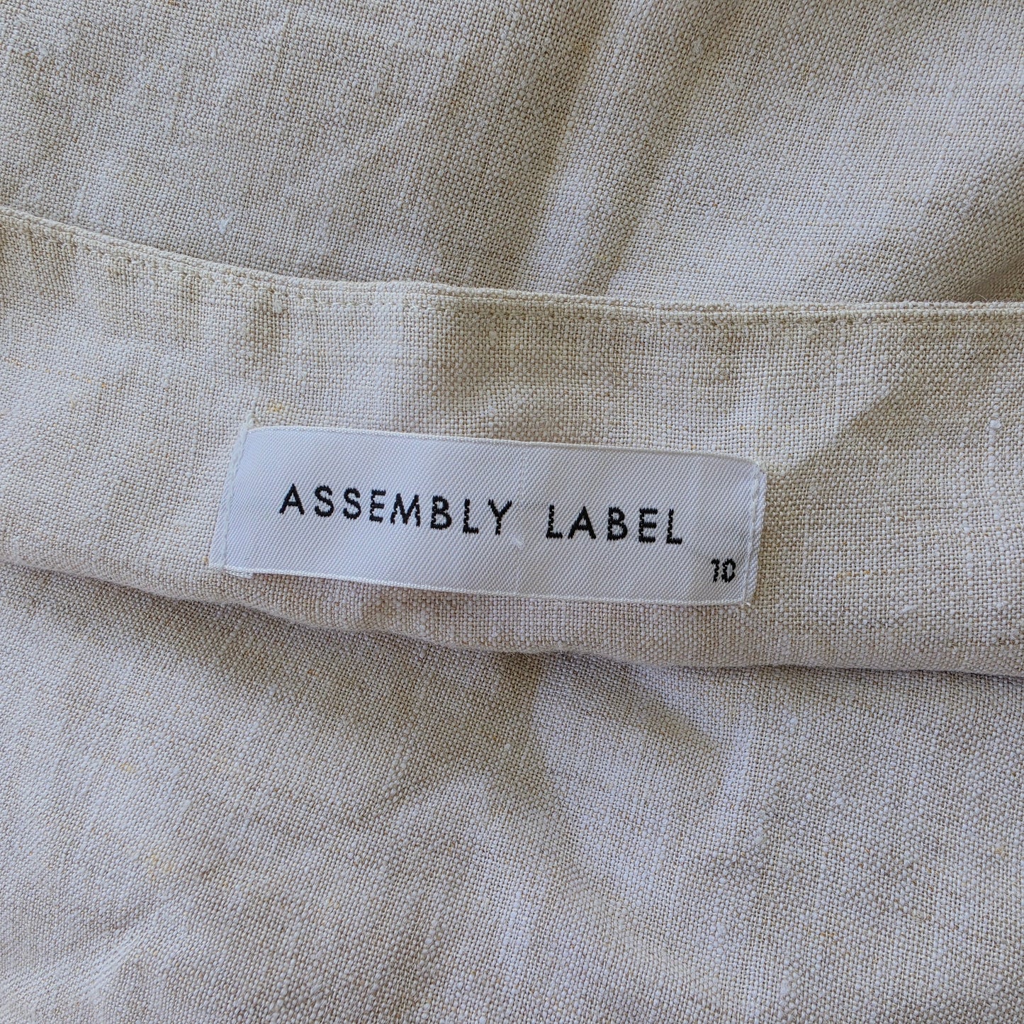 Close-up of a fabric label with 'Assembly Label' text on beige fabric.