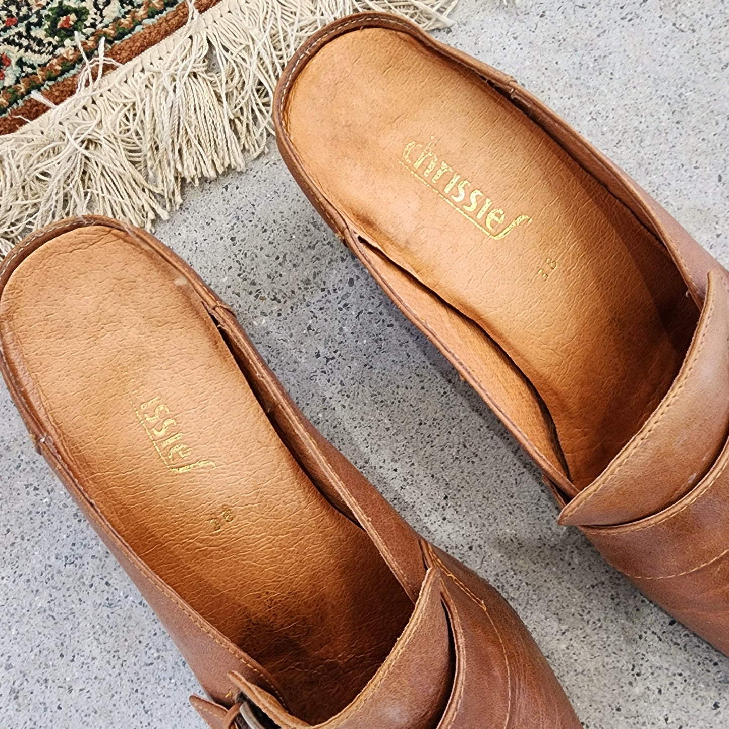 Top view of the Chrissie tan leather buckle mules, displaying the curved silhouette and padded leather insole.