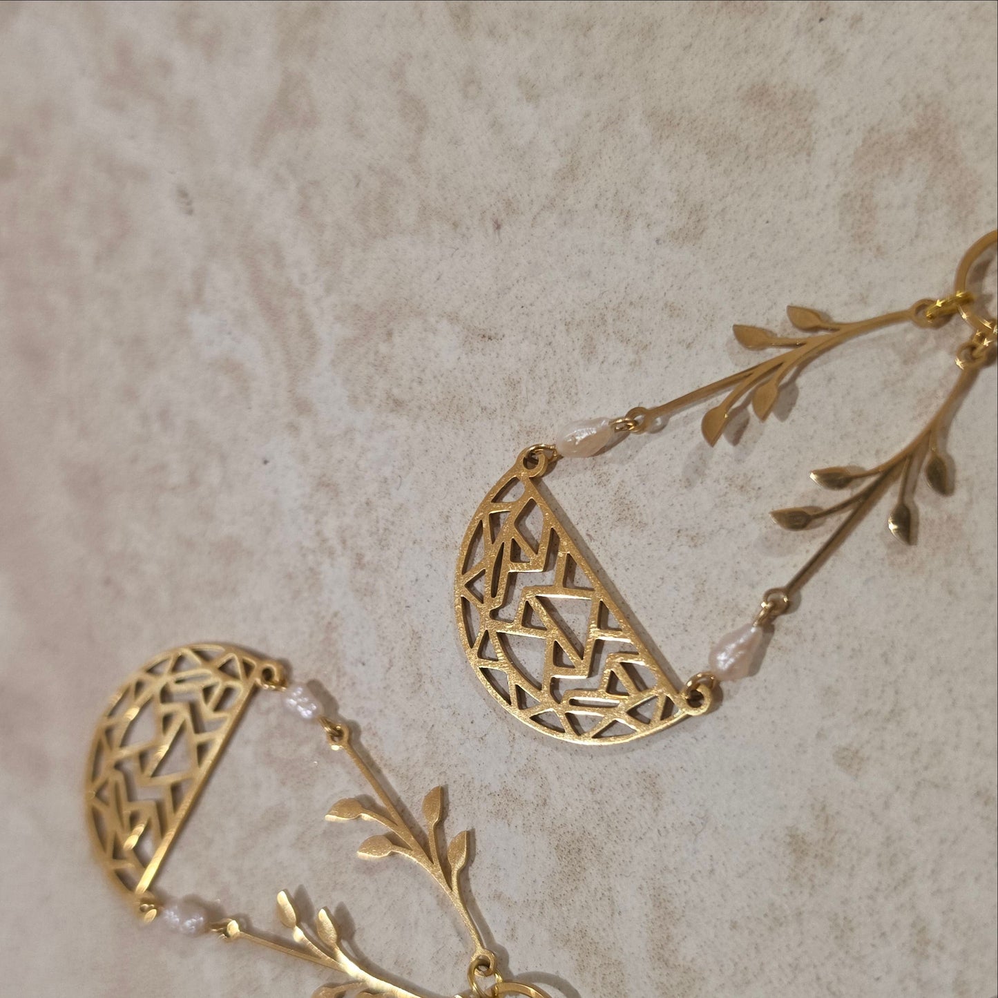 A close view of the top of the Coral handmade earrings showing the small natural pearls and gold plated components