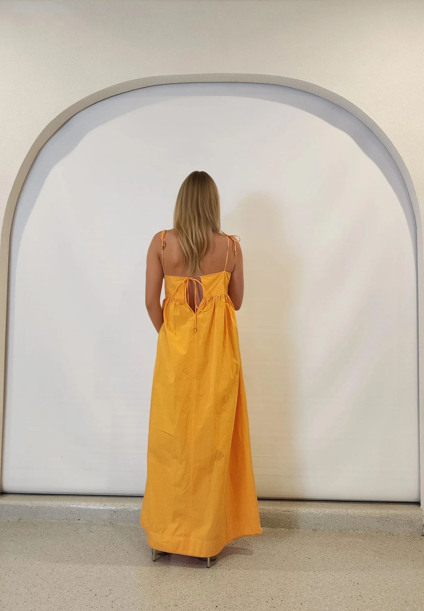 Back view of the Daisy Says marigold midi, showing tie-back and flowy silhouette.
