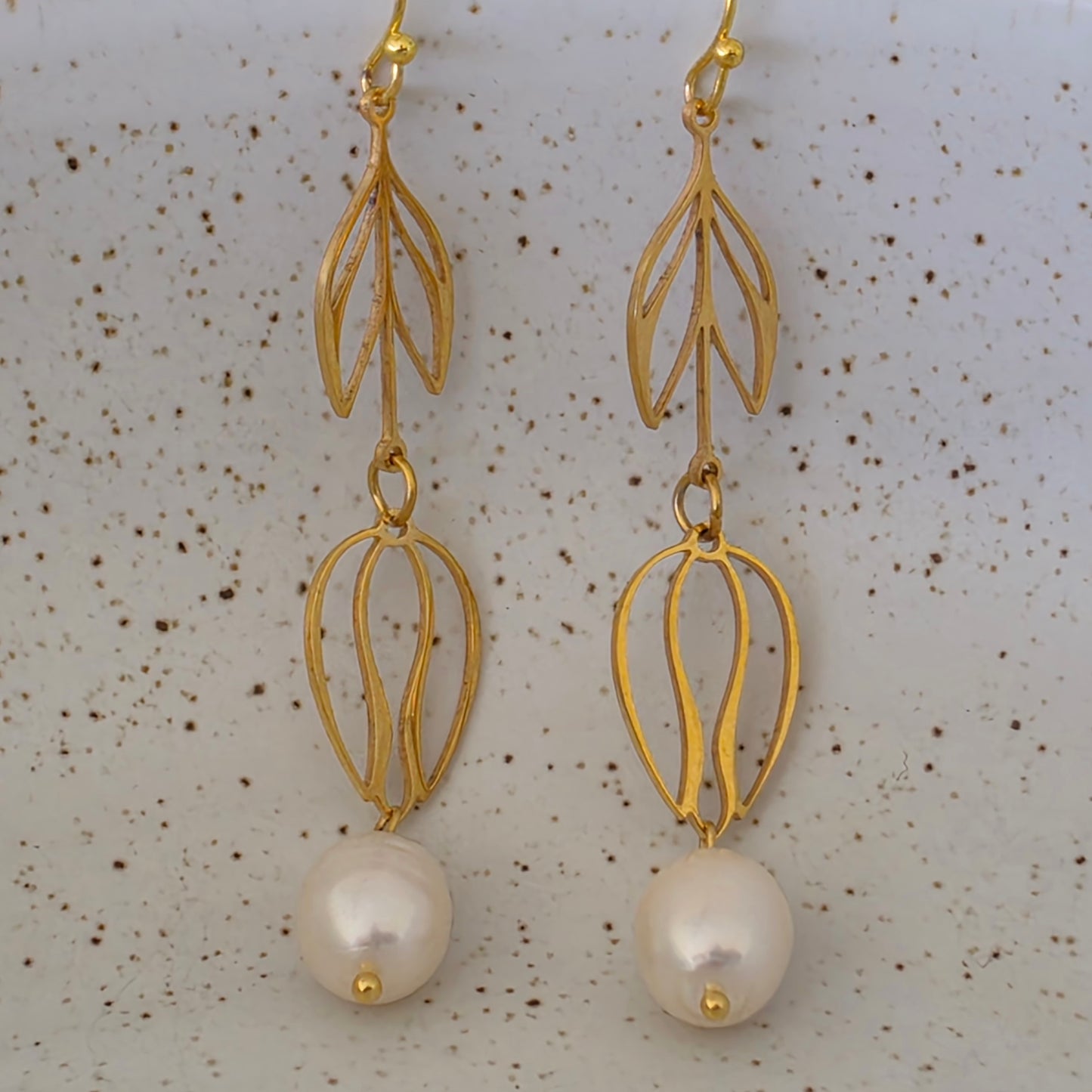 close view of the Dew handmade pearl earrings showing the bright sheen and uniquely shaped pearls. Suspended from flower drop gold plated stainless steel components.