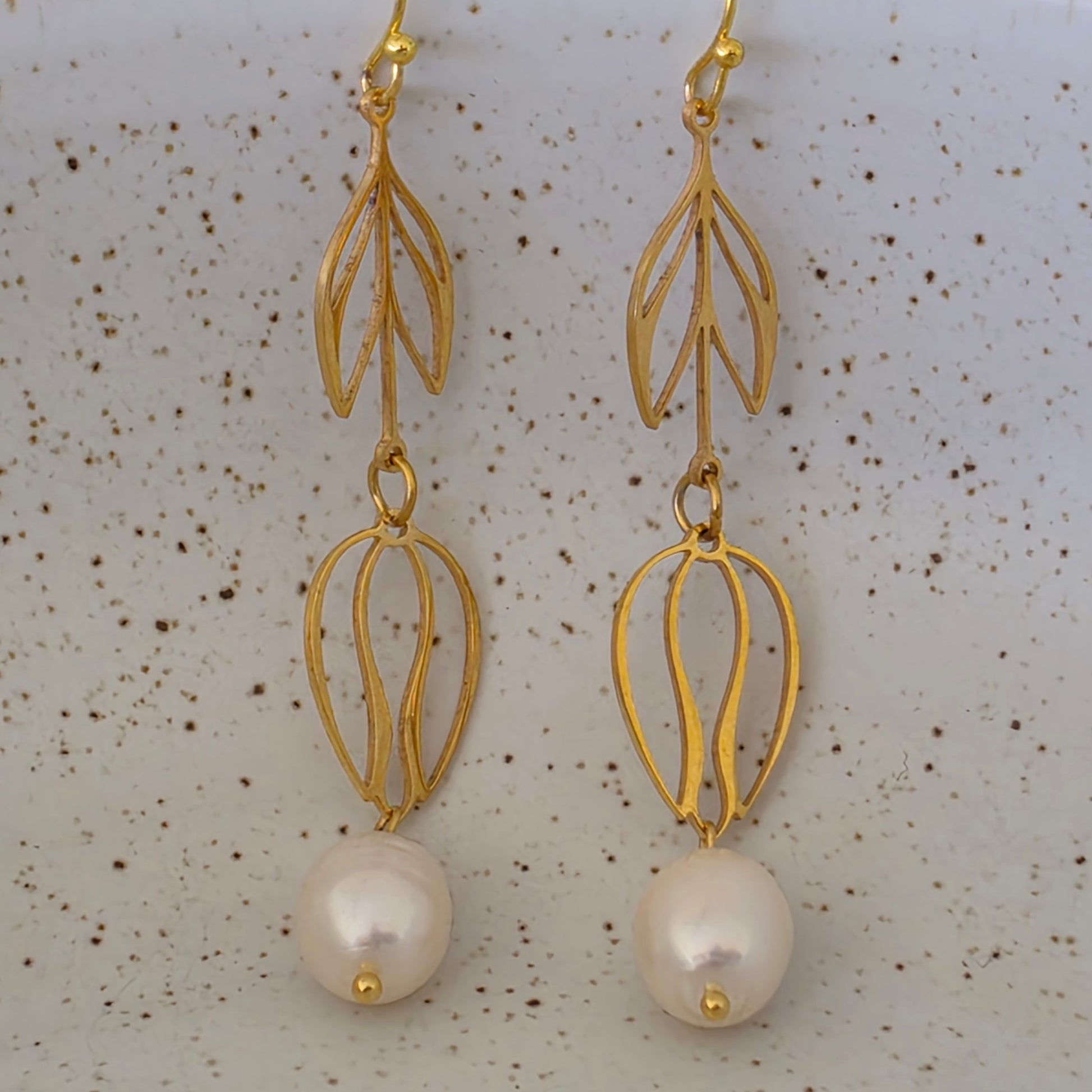 close view of the Dew handmade pearl earrings showing the bright sheen and uniquely shaped pearls. Suspended from flower drop gold plated stainless steel components.