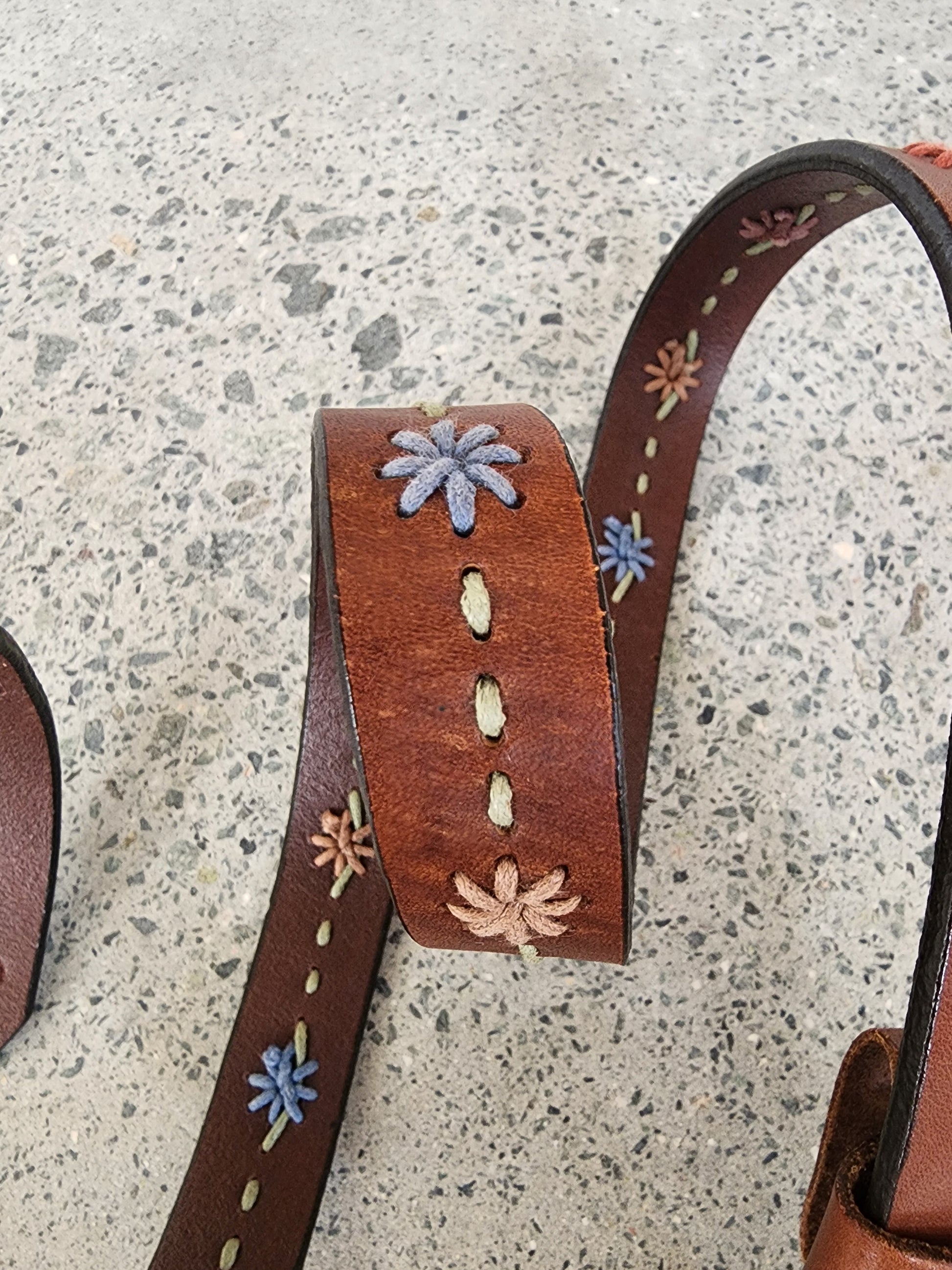 Close-up of Dockers leather belt showing stitched floral embroidery and rich tan leather.
