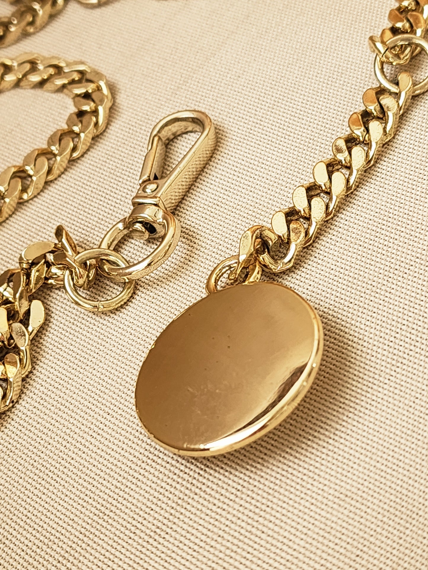 Close-up of Dylan Kain 88 chain belt gold medallion with light surface scratching.