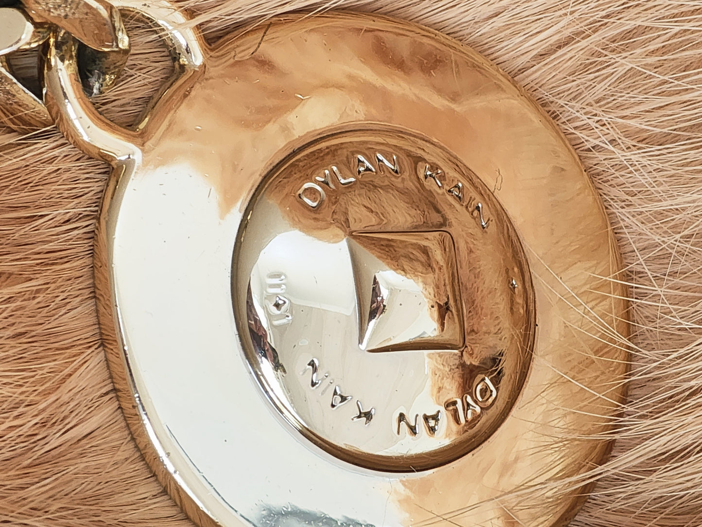 Close-up of Dylan Kain 88 chain belt gold medallion with surface scratching.