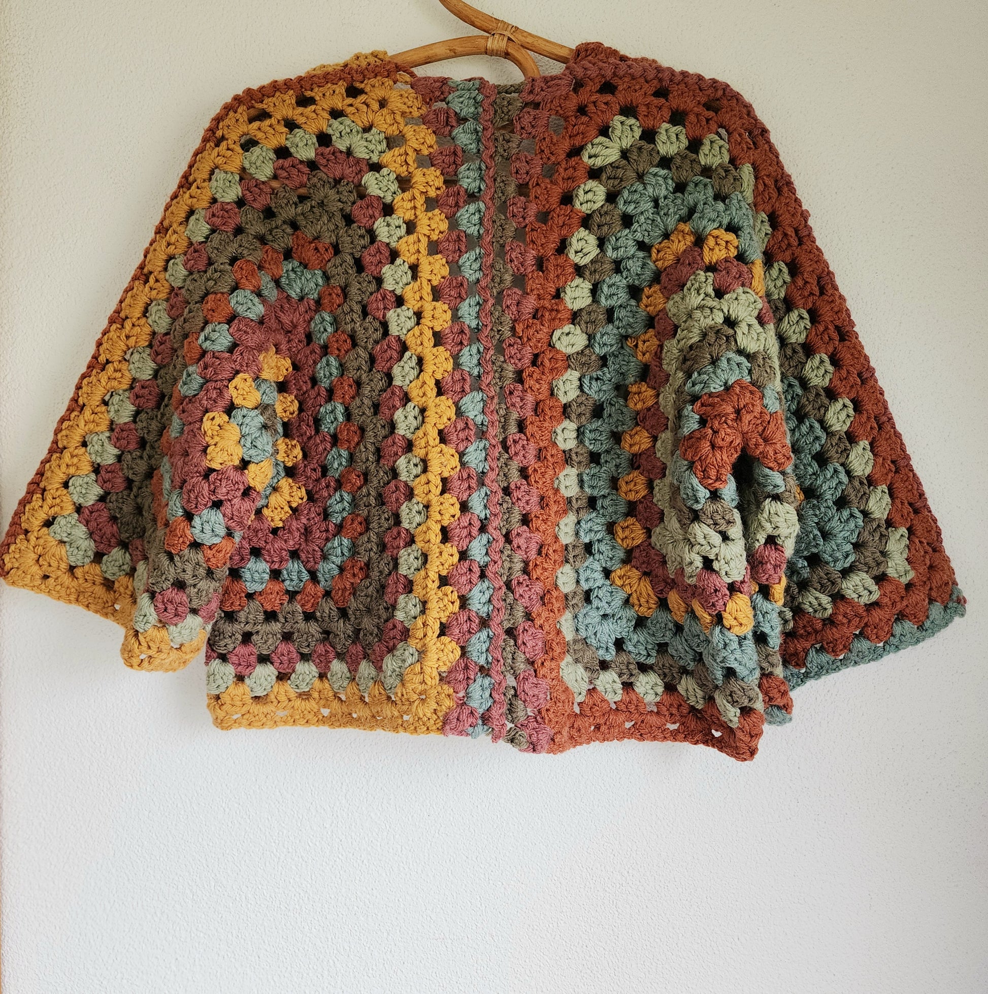 Back view of earth-toned crochet cardigan with oversized granny square pattern in rustic autumn colours.
