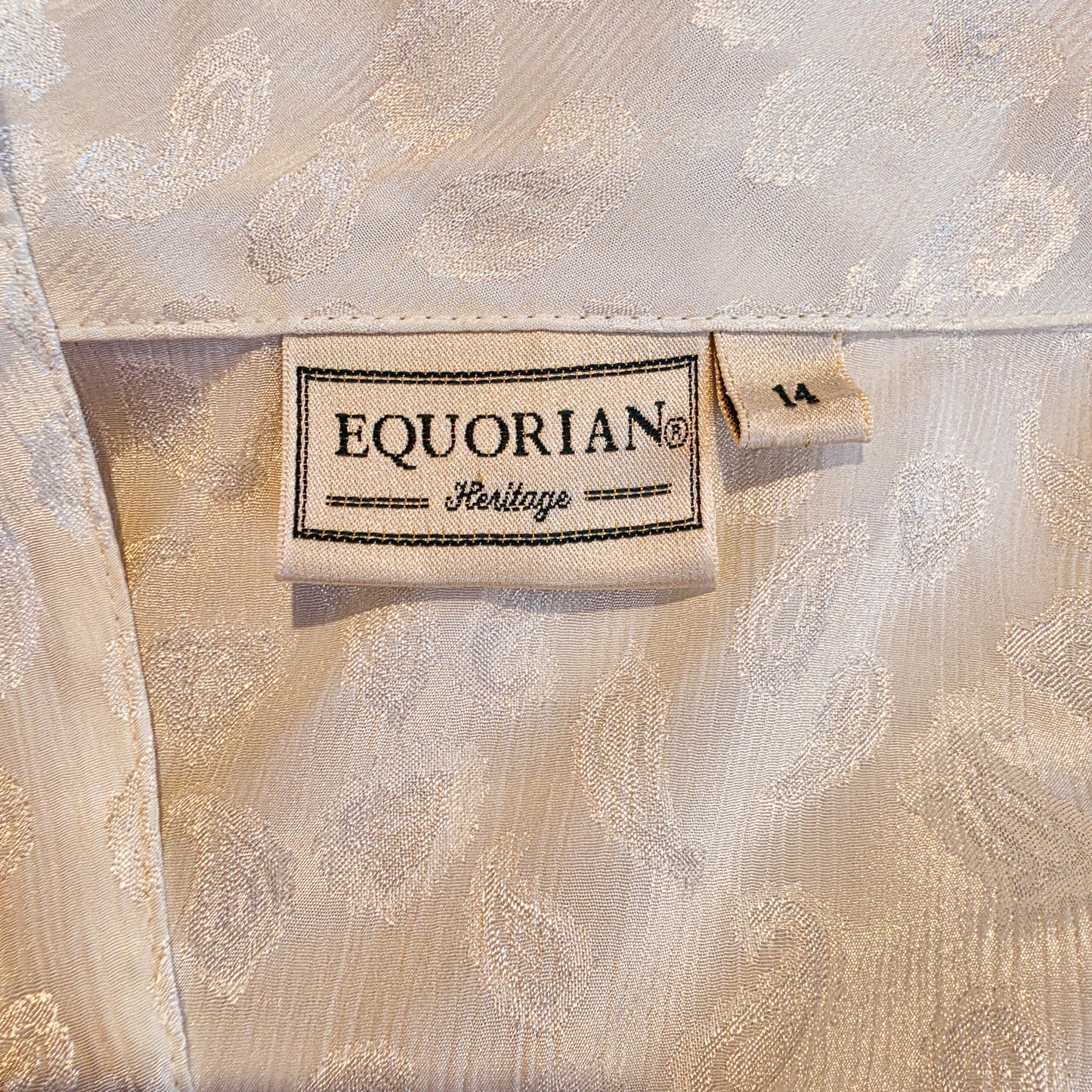 Close-up of a cream-colored jacquard blouse with a visible Equorian Heritage brand label.