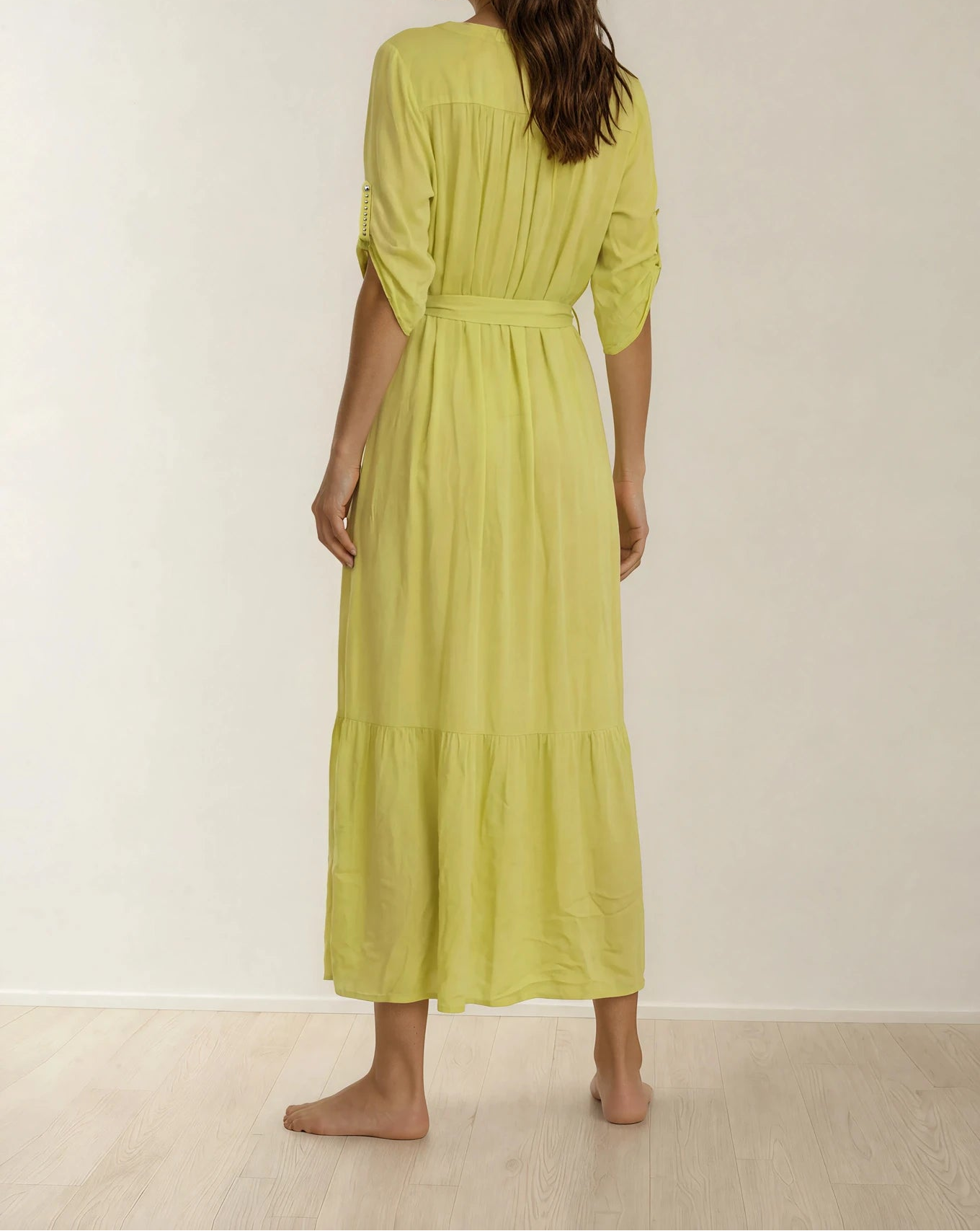 Model showing the back of the Eva Kayan button up dress, showing the adjustable sleeves, belt and tiered hemline.