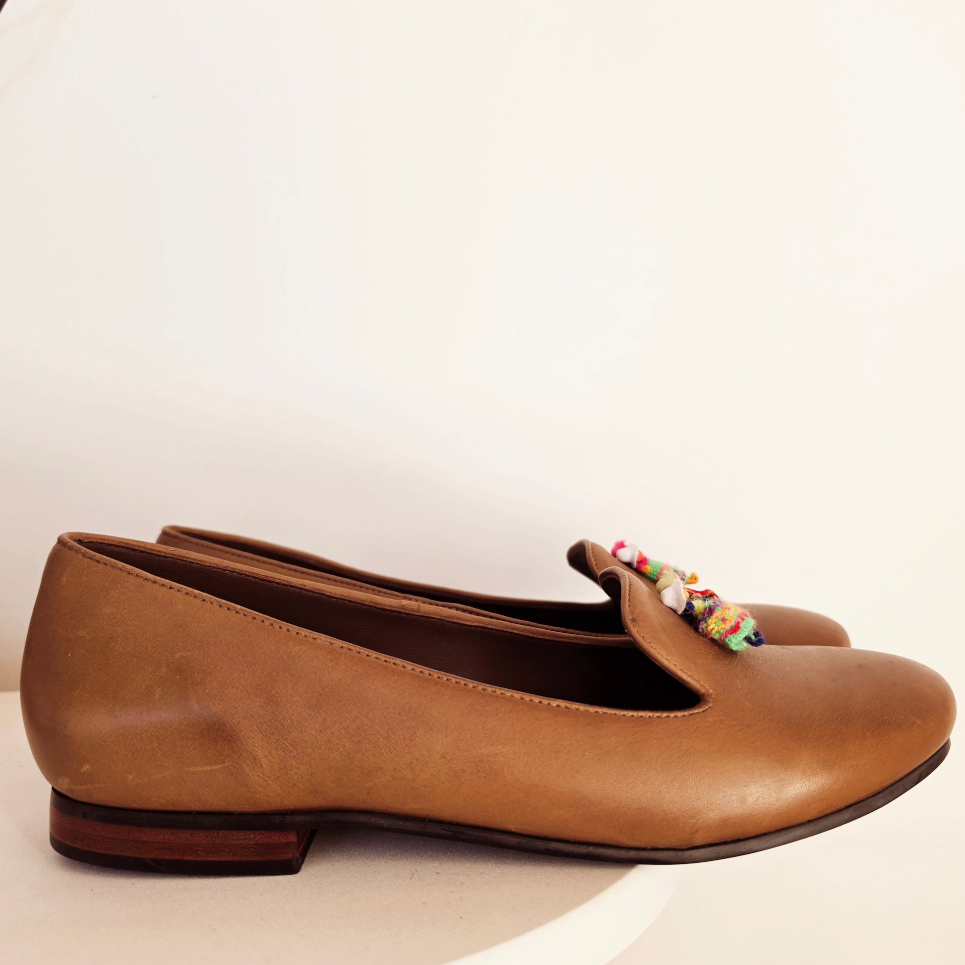 SIde view of the Fortress of Inca tan leather Smking flats, with a small Andean dolls on the vamp.