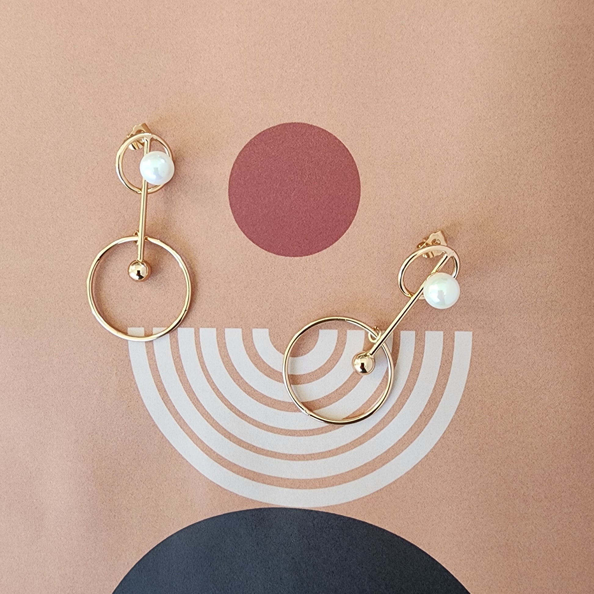 Slightly angled image showing the drop design and polished gold-tone finish of the Golden Orbit earrings