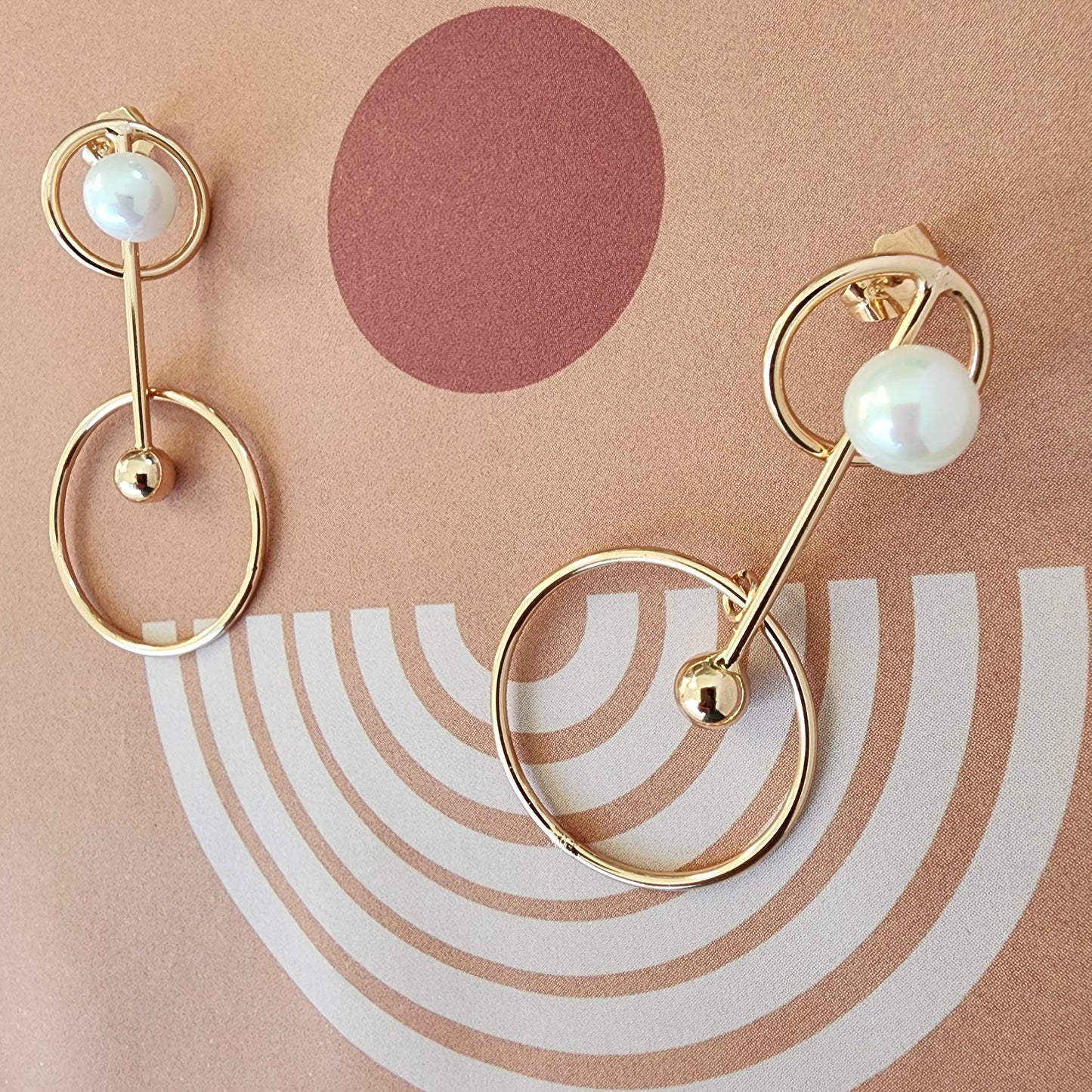 Front view of the Golden Orbits earrings with geometric gold circles and faux-pearl detail.