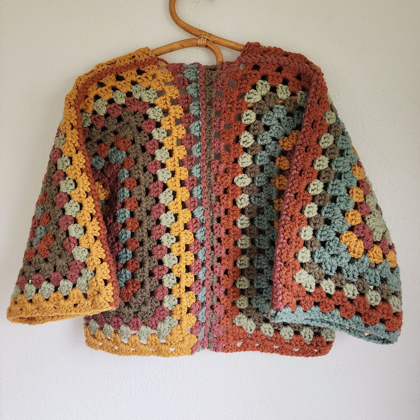 Back view of earth-toned crochet cardigan with oversized granny square pattern in rustic autumn colours.
