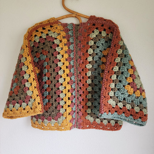 Back view of earth-toned crochet cardigan with oversized granny square pattern in rustic autumn colours.