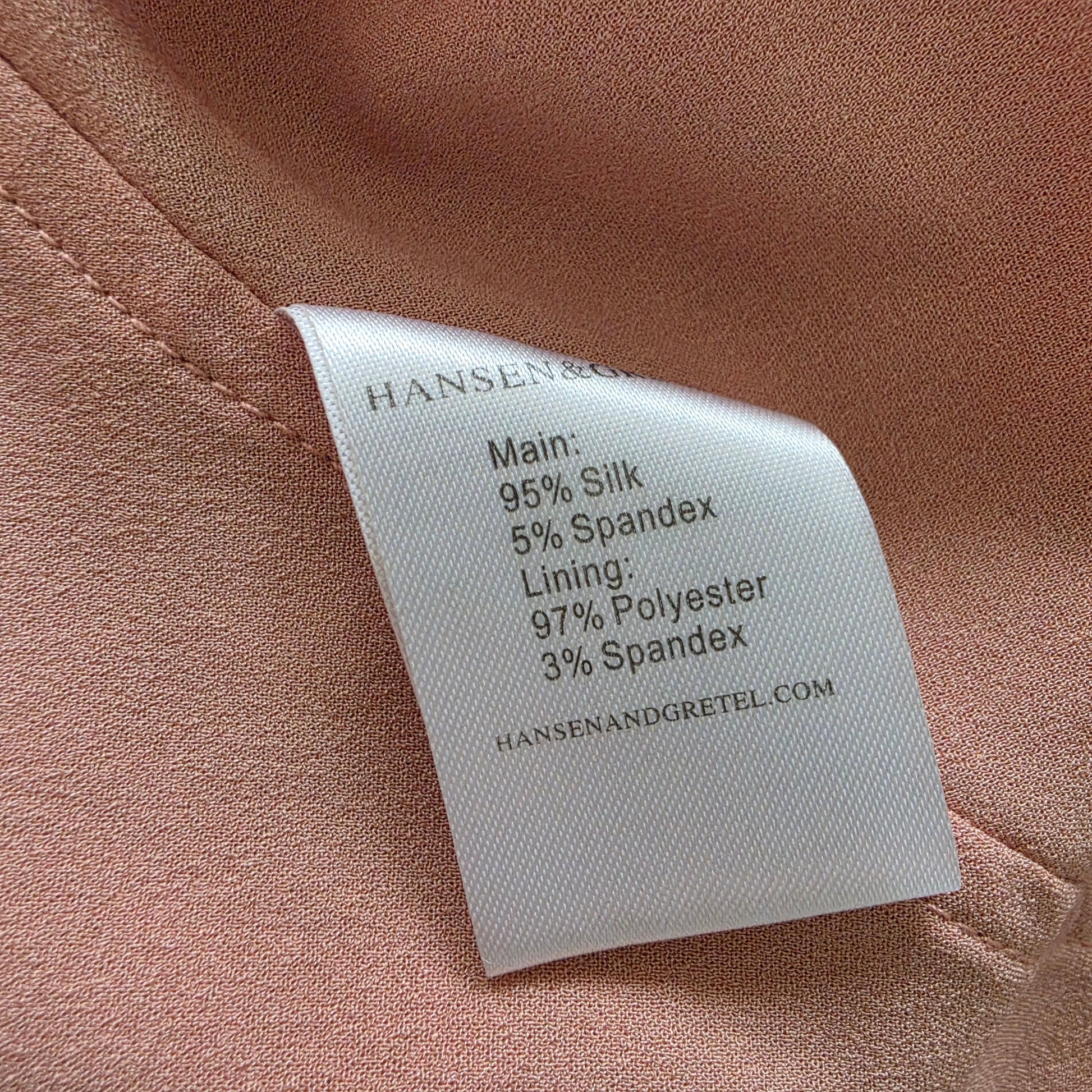 A close-up of the fabric care label sewn onto the Hansen & Gretel slip dress. The label lists materials including 95% silk, 5% spandex, 97% polyester, and 3% spandex.
