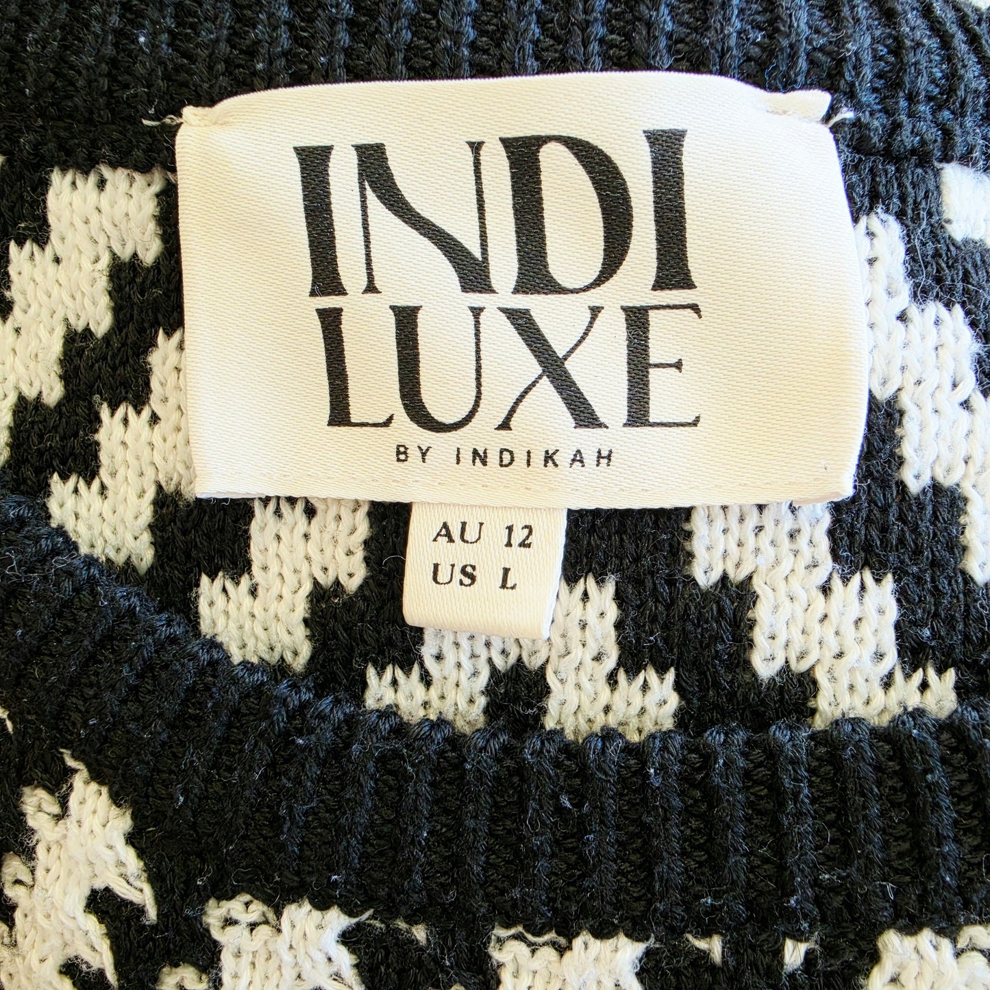 Image showing the brand label for the Indi Luxe knit dress by Indikah. The image also shows light pilling at the neckline.