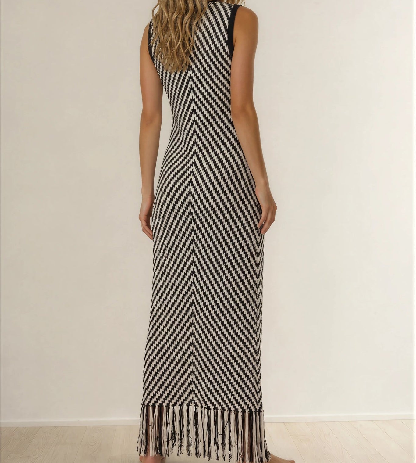 Model showing the back view of the Indi Luxe monochrome knit dress, showing the fringe hemline