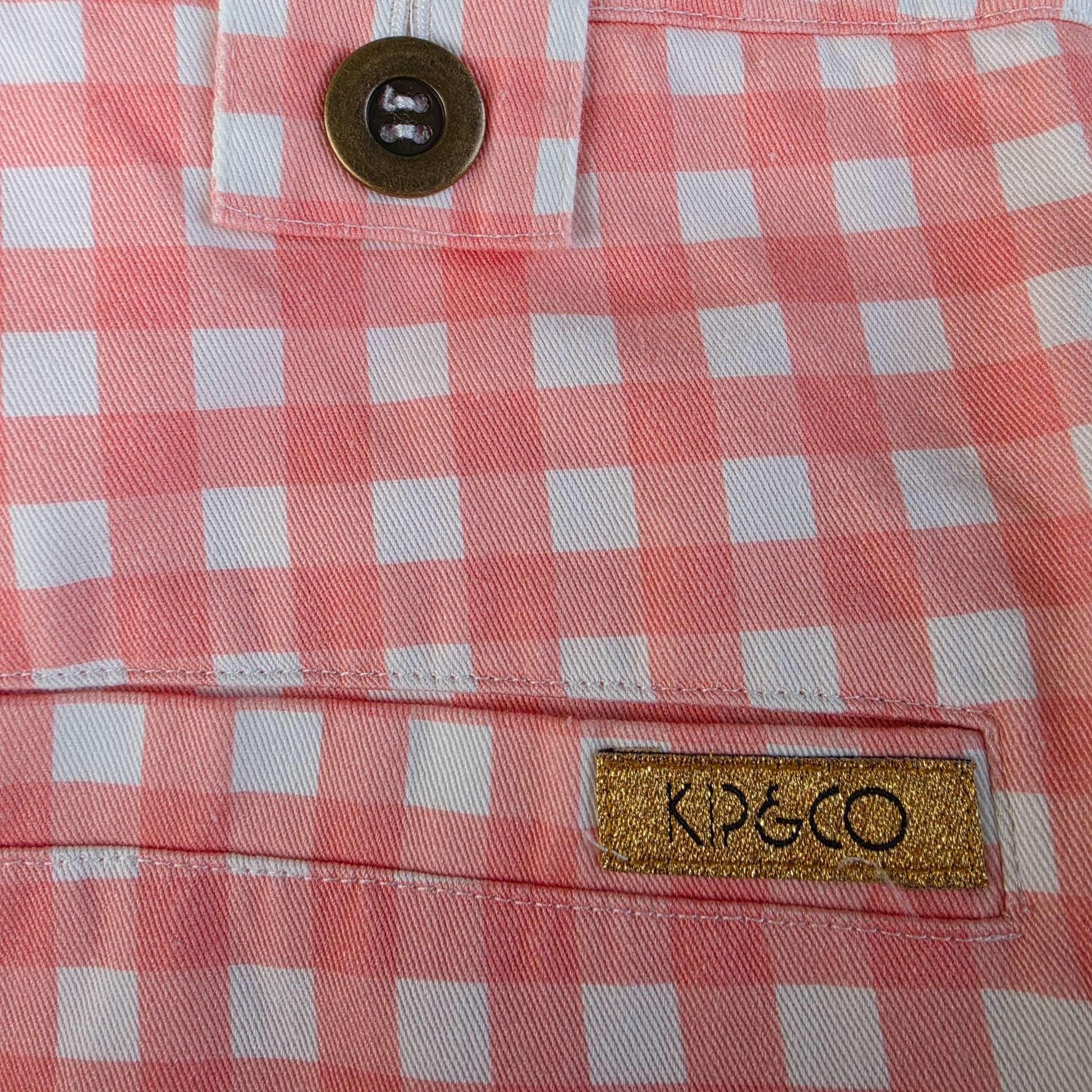 Close-up view of the gold label on the Kip & Co. Candy Gingham Pants
