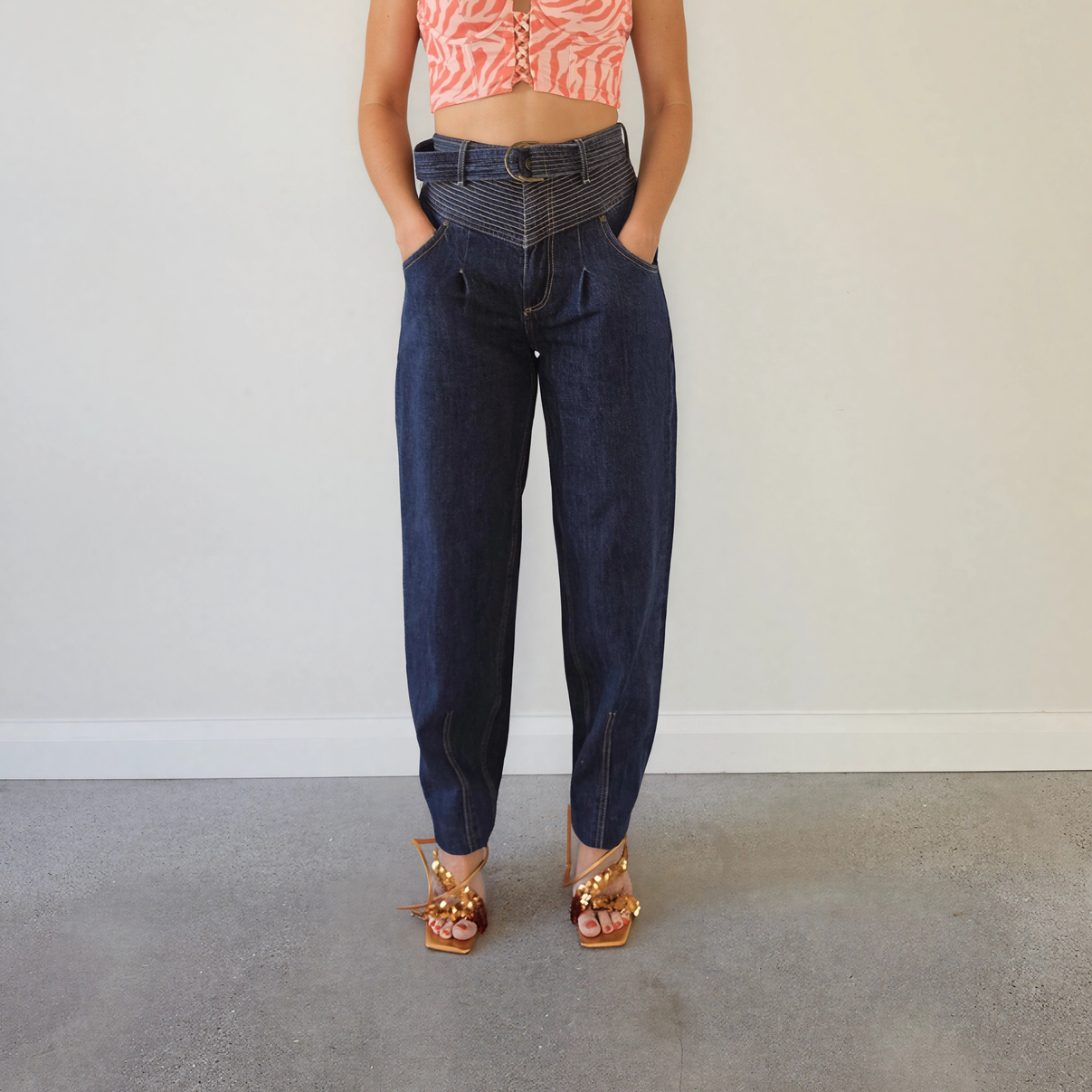  The front view of a woman wearing the Kivari Adina Jeans in Indigo, showing the high waist, belted style and tapered leg.