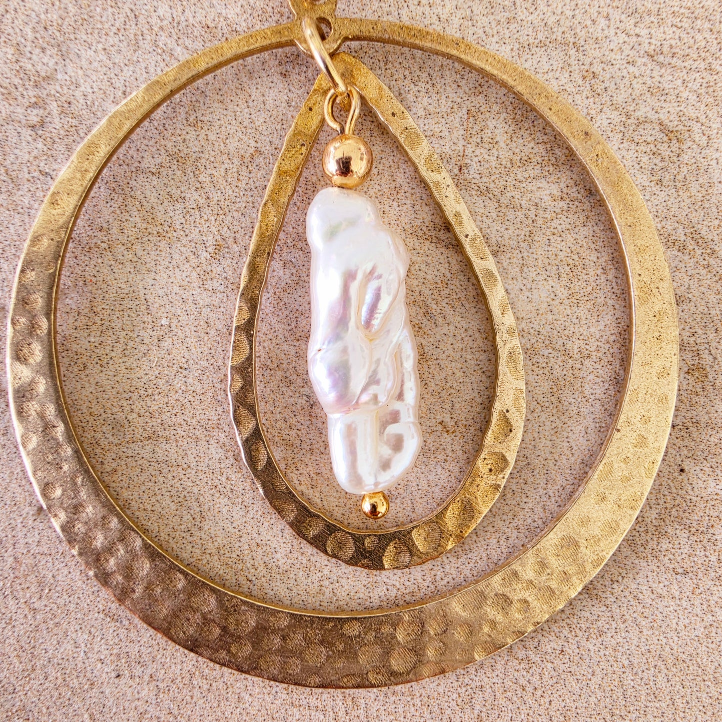 Close up view of the Kolekti earrings showing the hammered gold texture and feature pearl.